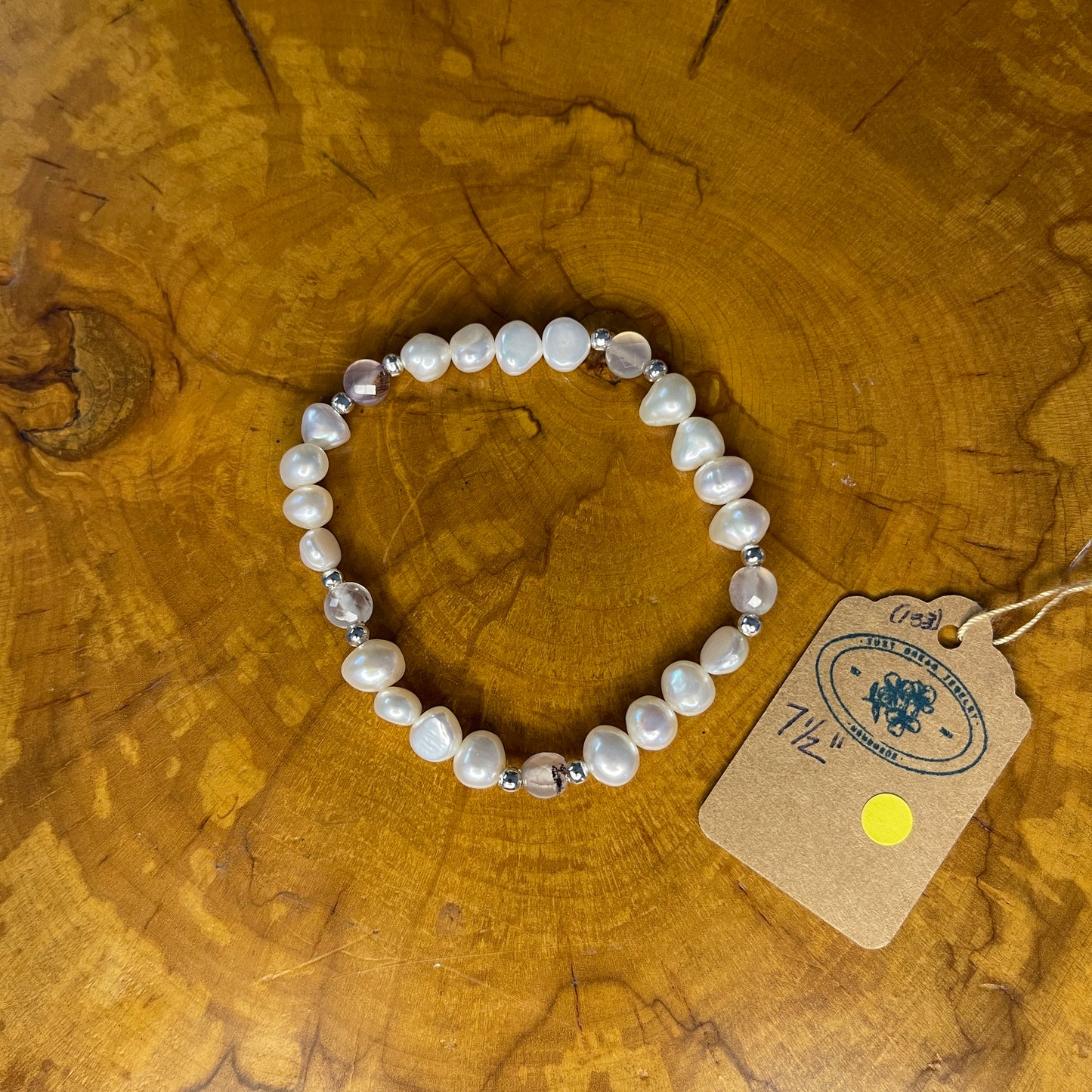 White freshwater Potato Pearls with Pink faceted Jasper on elastic, 7 1/2"on a wooden surface with tag