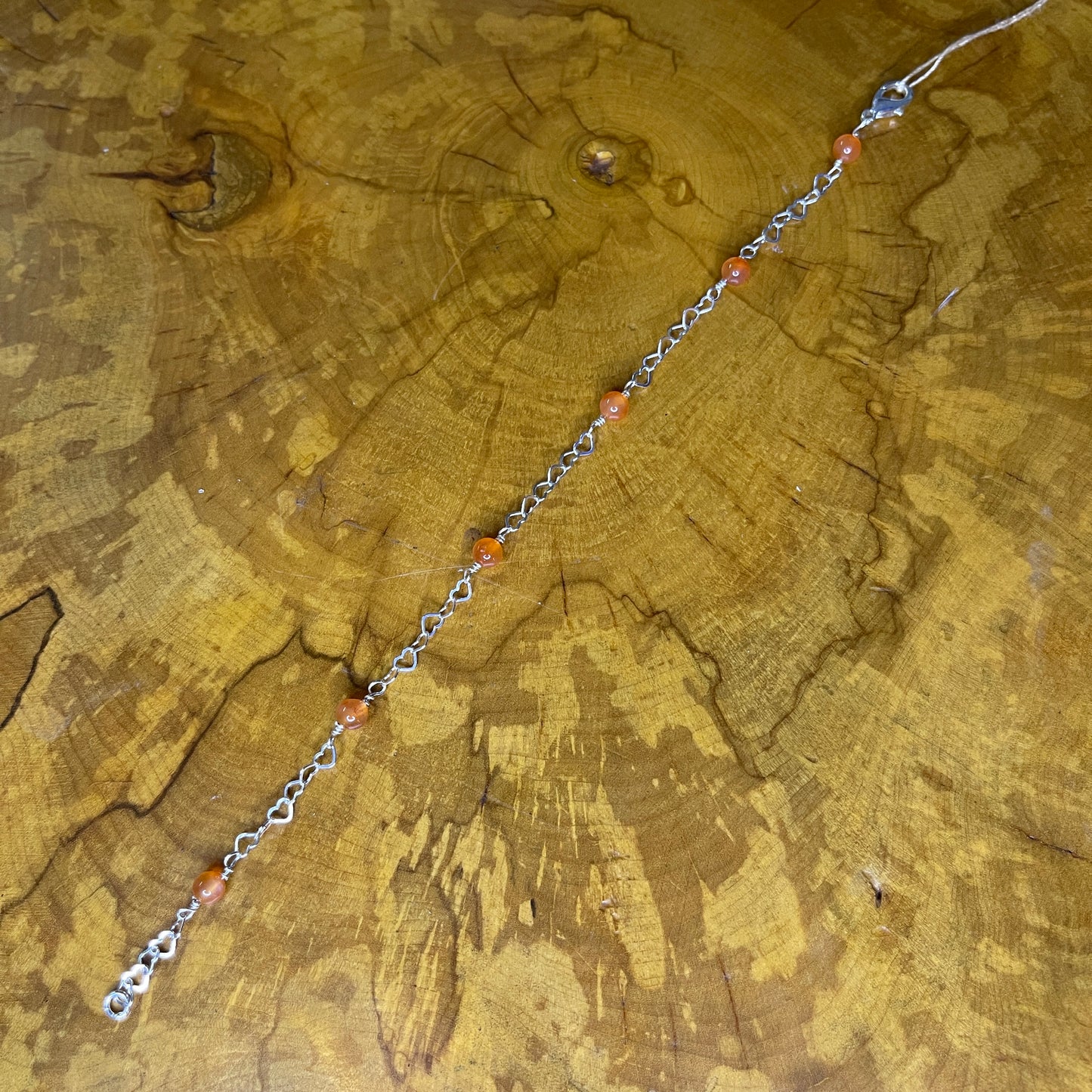 Carnelian rounds on Sterling Silver wire and Sterling Silver Heart Chain 8 1/2", Sterling Silver Lobster clasp on wooden surface