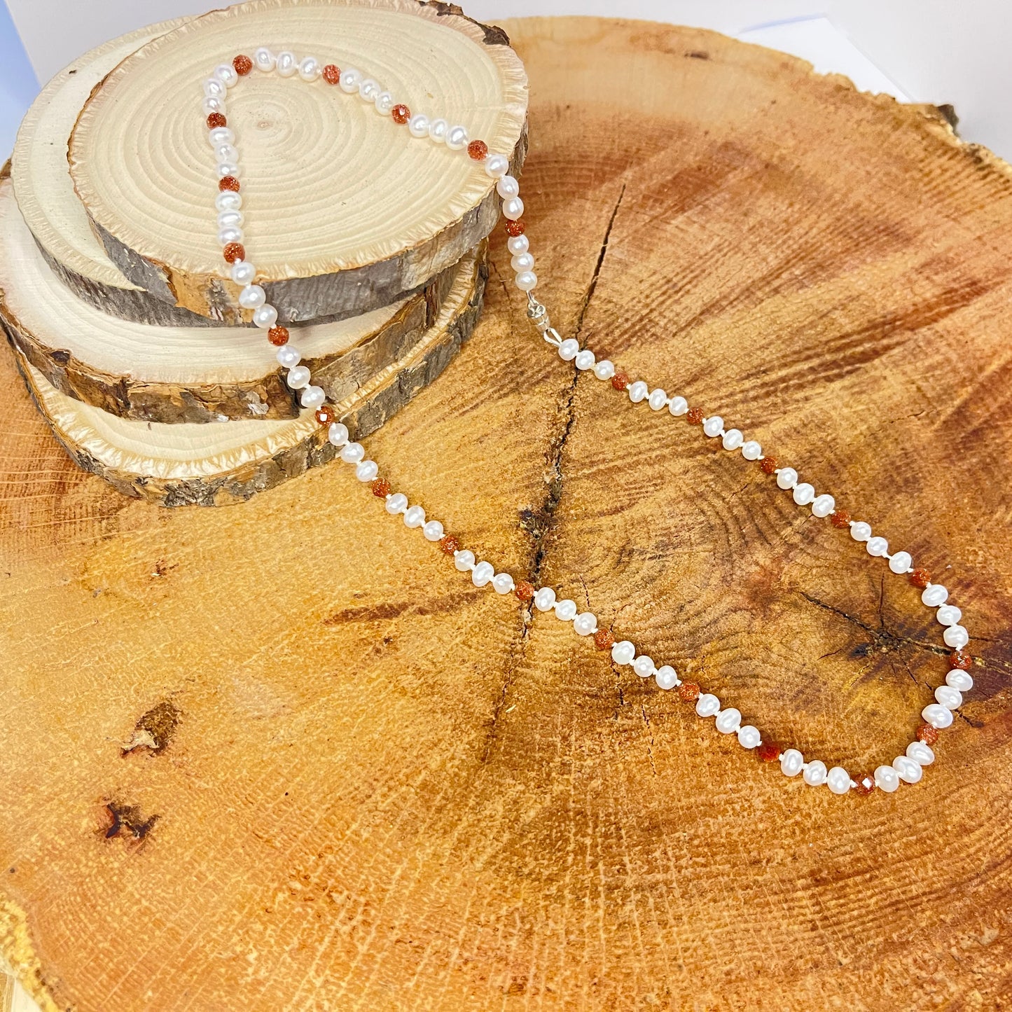 Pearl and Goldstone necklace on a wooden surface