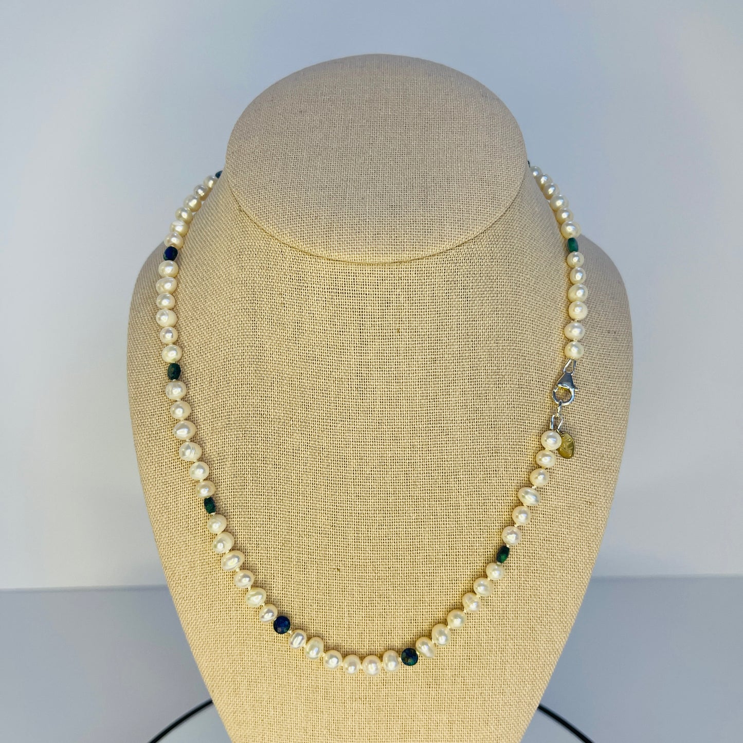 Pearl necklace on a mannequin bust against a plain background