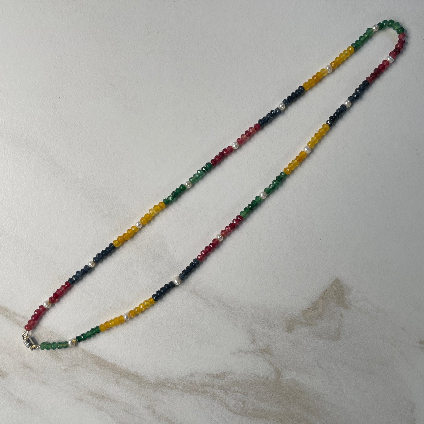 Multicolored Jade and White Pearl necklace on white marble