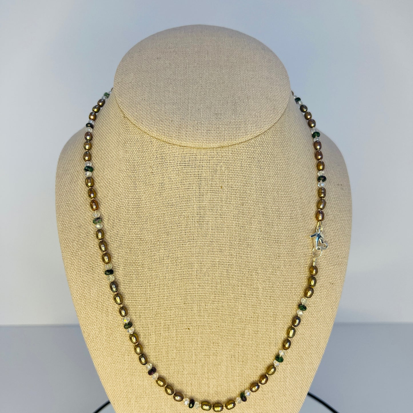 Brown Pearl, green jasper and crystal Necklace with a Silver heart shaped clasp on a mannequin bust with a plain background