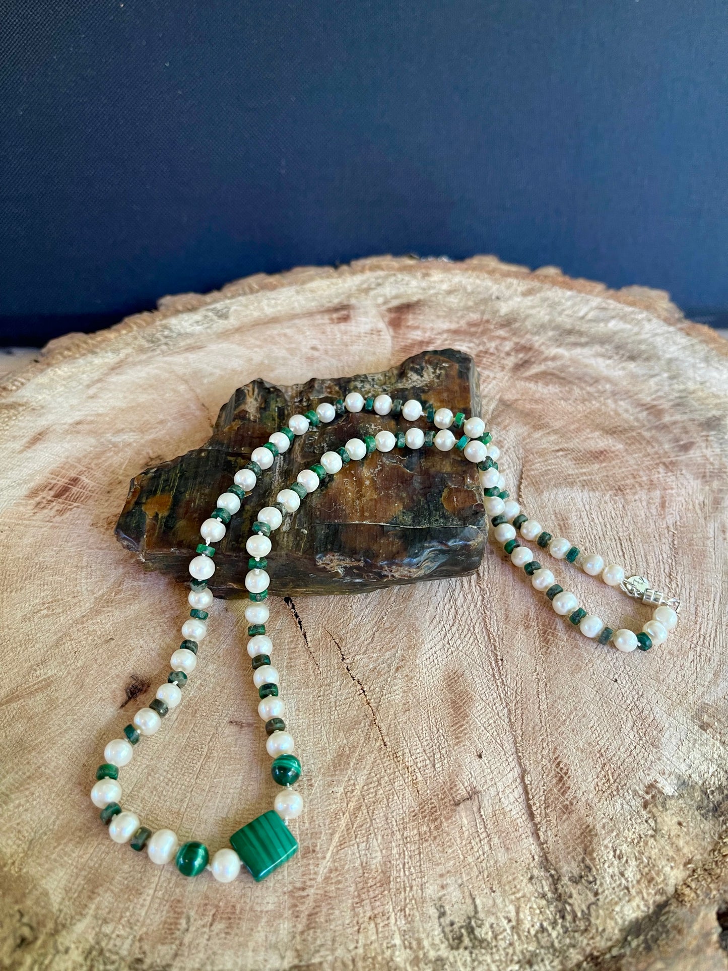 Necklace of Malachite and White Pearls beads on a wooden surface with natural elements