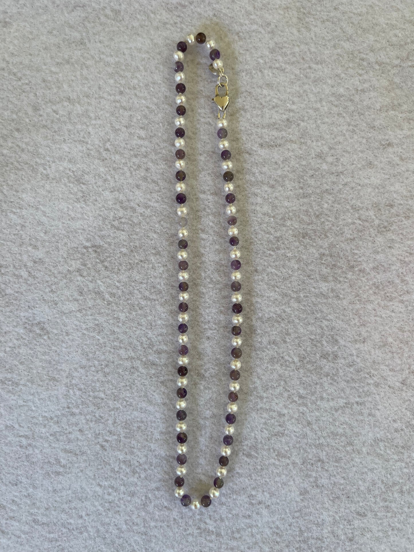 Necklace with alternating White Pearl and Amethyst beads on a gray background