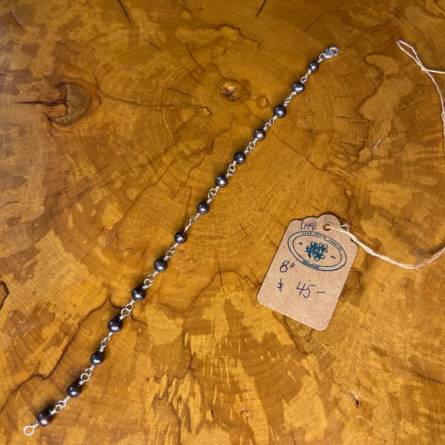 Peacock Freshwater pearls on Sterling Silver wire, 8" w/ Sterling Silver lobster clasp on wooden surface
