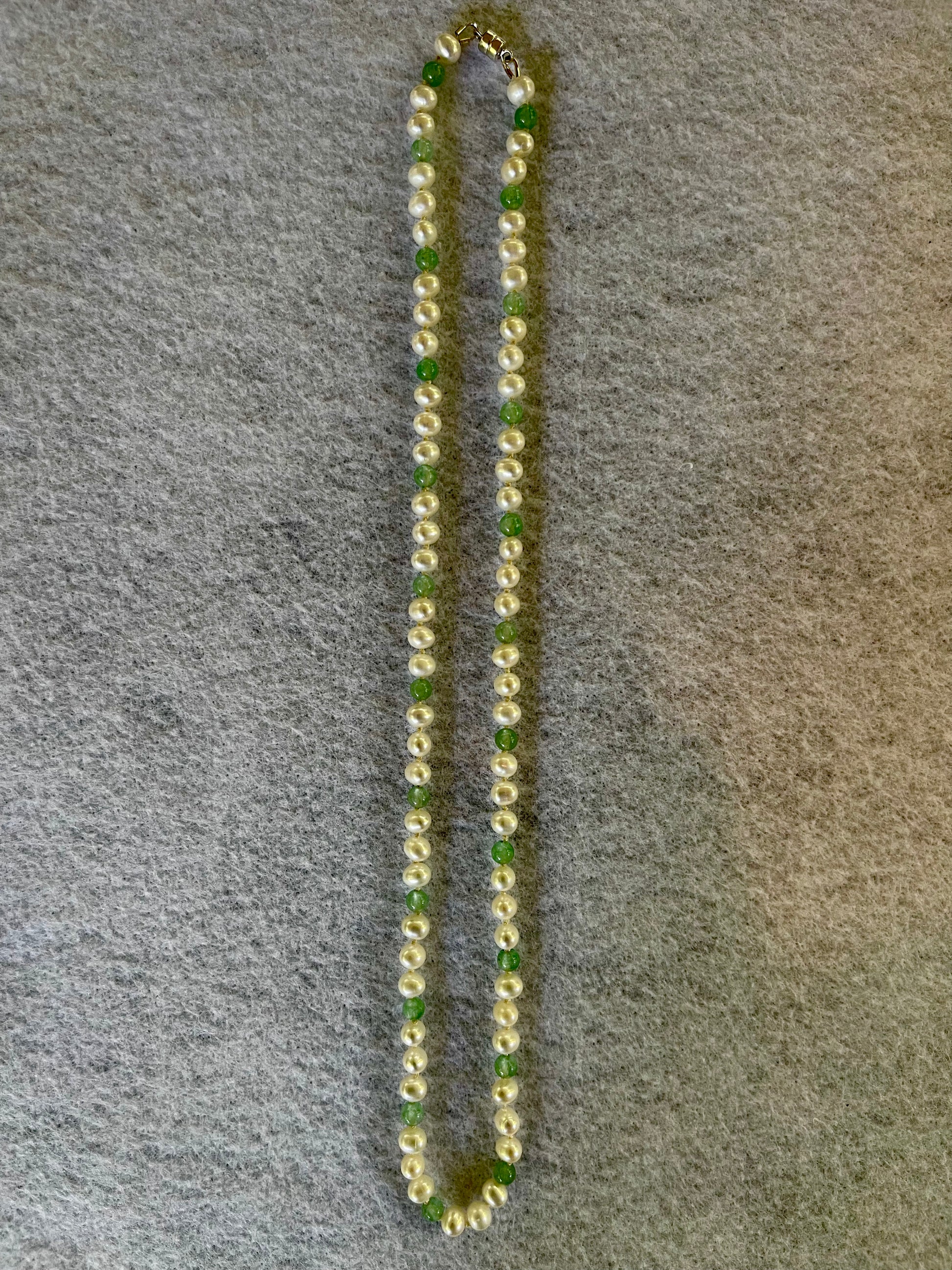 Necklace with green and white beads on a gray surface