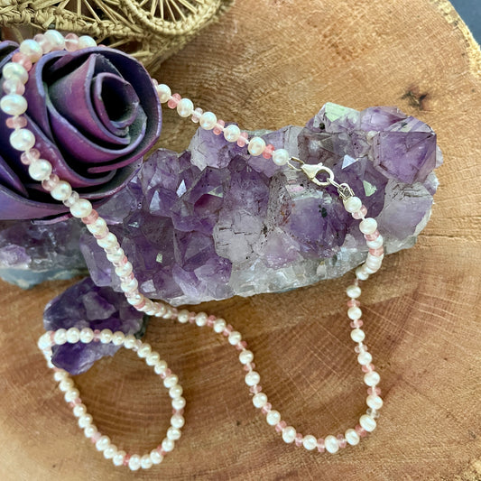 White Pearl  and strawberry quartz necklace and matching stretchy bracelet on a wooden surface with purple crystals and a purple rose.