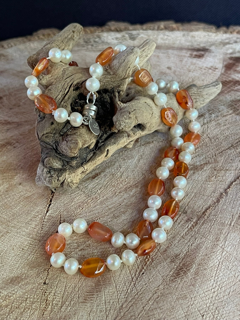 Necklace with White Pearls and oval Carnelian beads(shown without matching stretchy bracelet) on a wooden surface with driftwood
