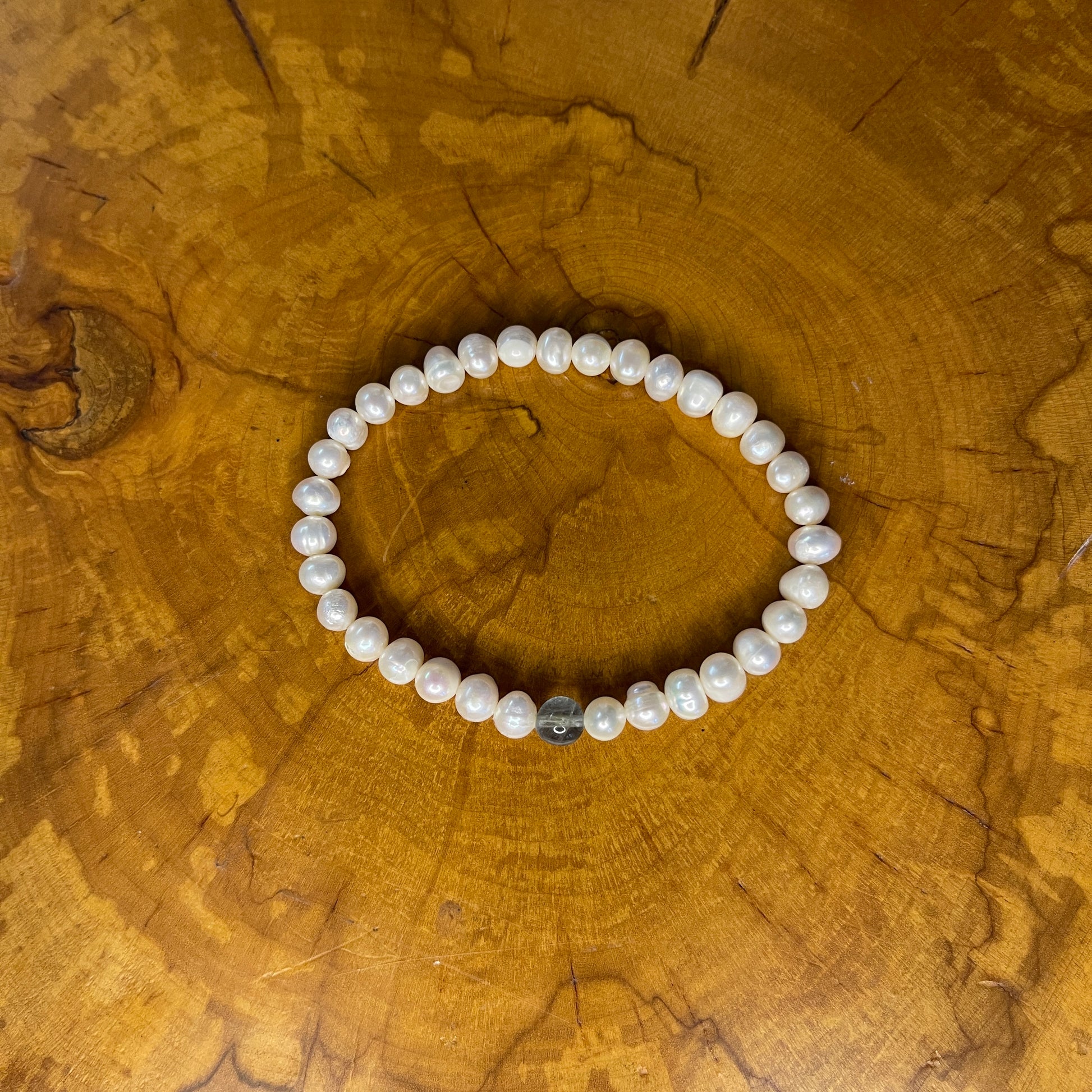 Freshwater White Pearls with Fluorite focus bead on elastic, 7 1/2" on wooden surface