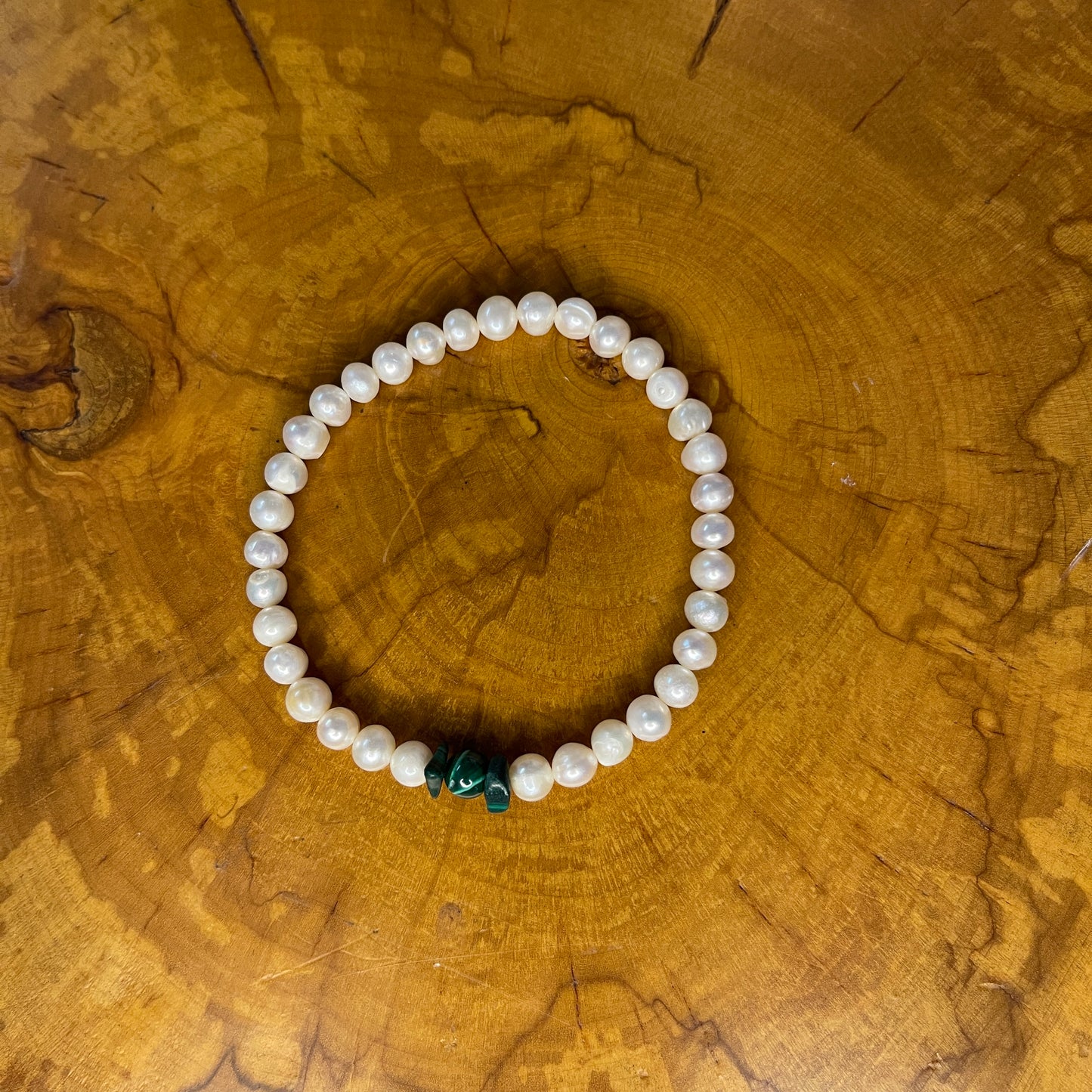White Freshwater pearls with Malachite focus beads on elastic ,7 1/2" on wooden surface
