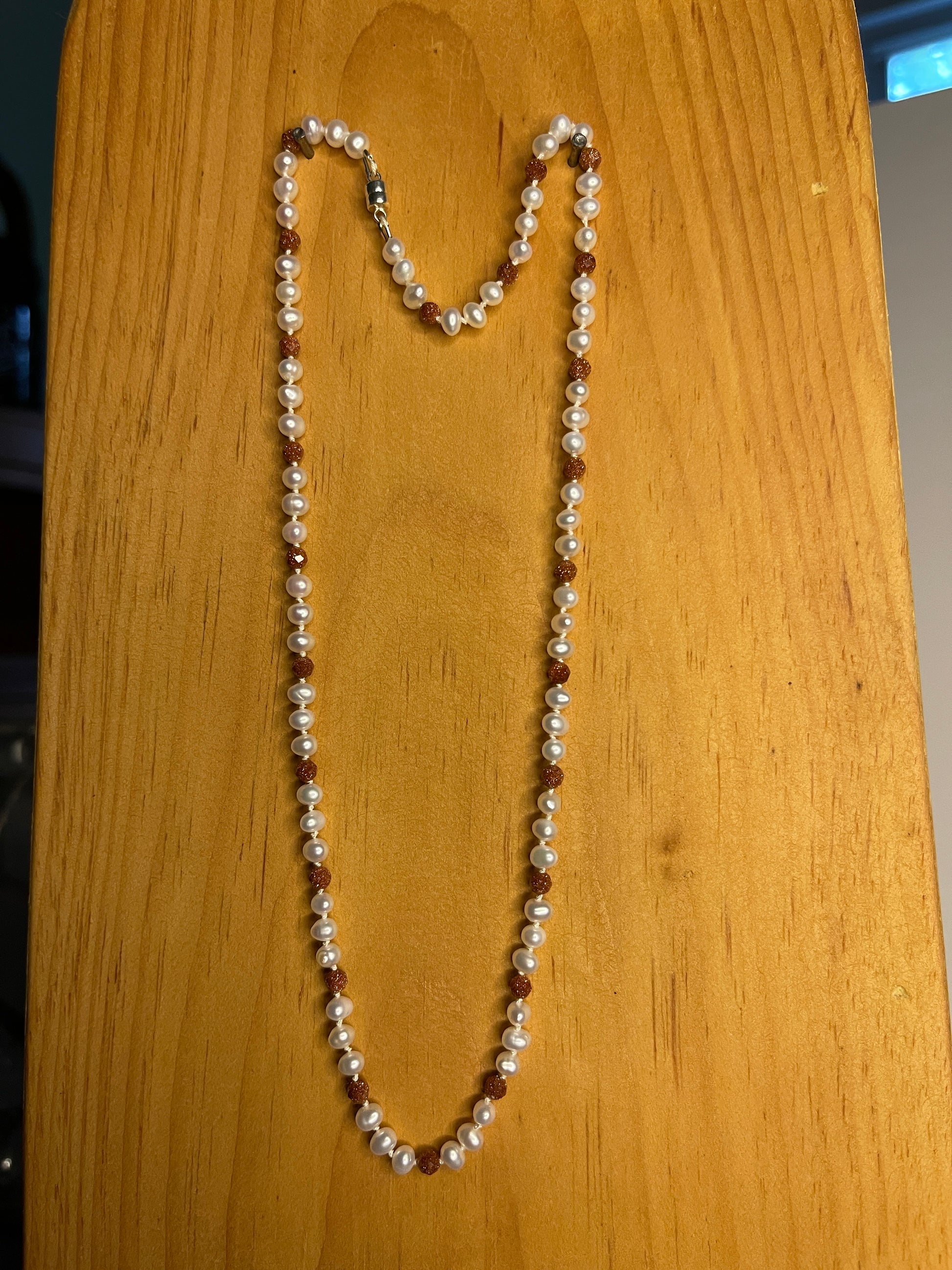Pearl  and Goldstone necklace on a wooden surface