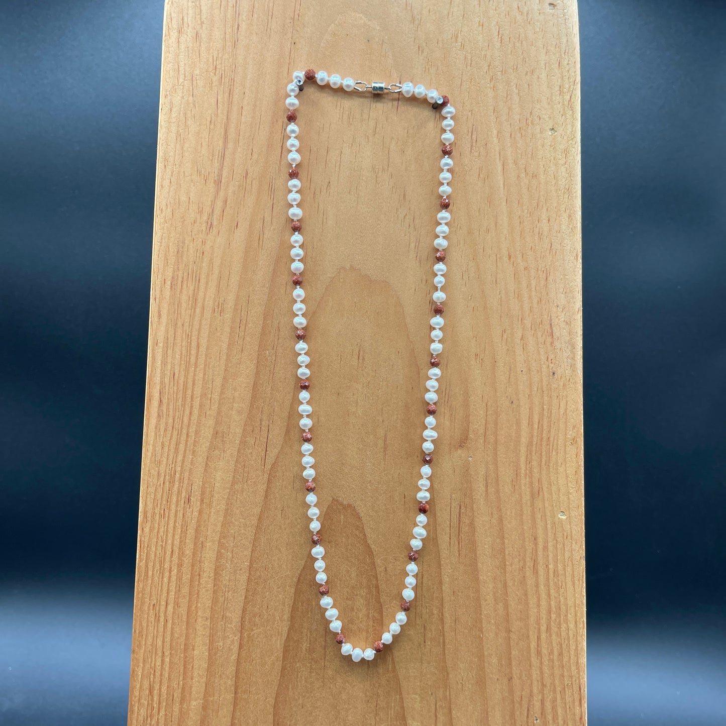 Pearl  and Goldstone necklace on a wooden surface