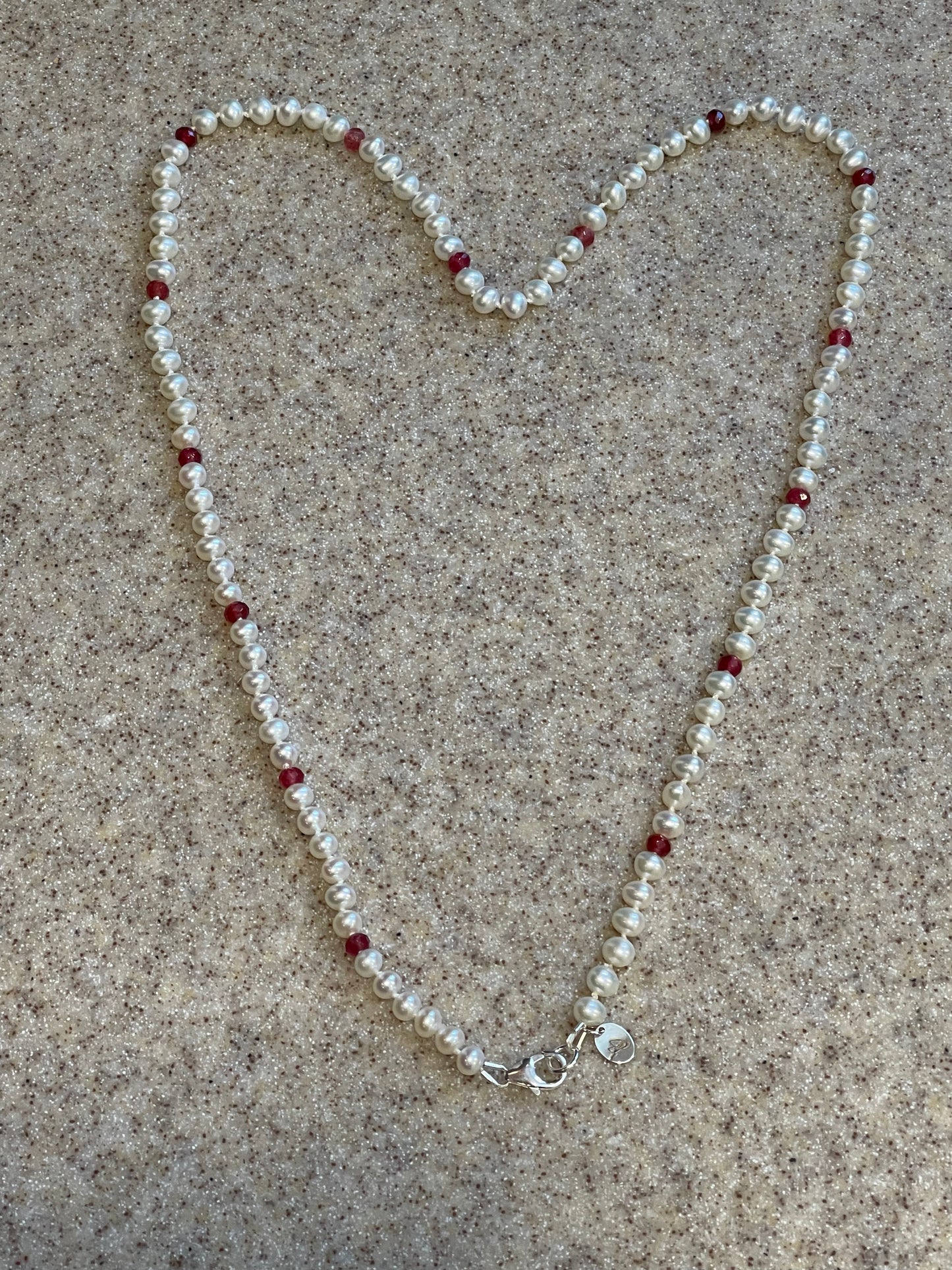 Necklace forming a heart shape on a sandy surface