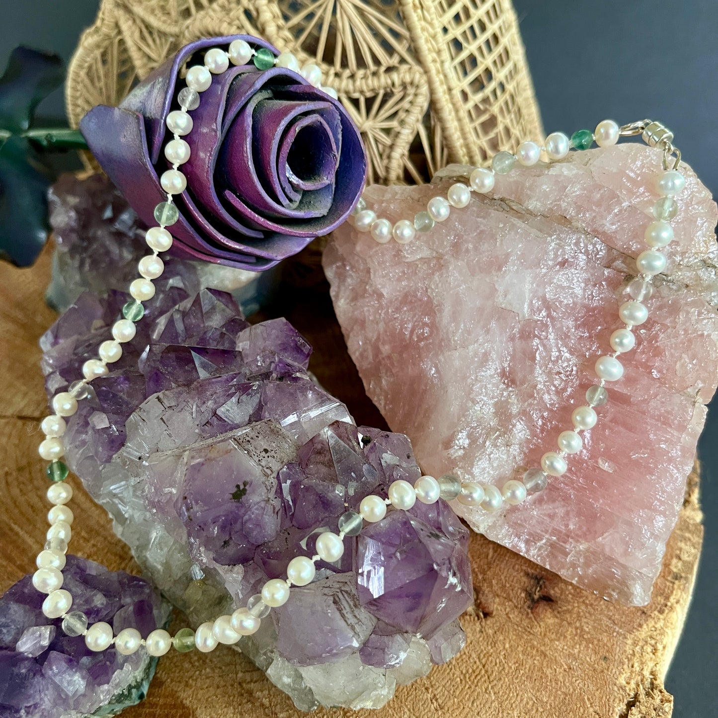 Pearl  and fluorite necklace on a display with purple flowers and crystals