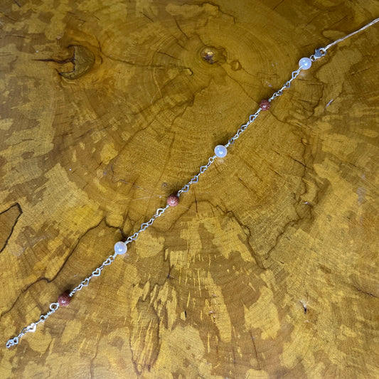 Goldstone and Freshwater White Pearls on Sterling Silver heart Chain, 8 inches with 1/2 inch extender on a wooden surface