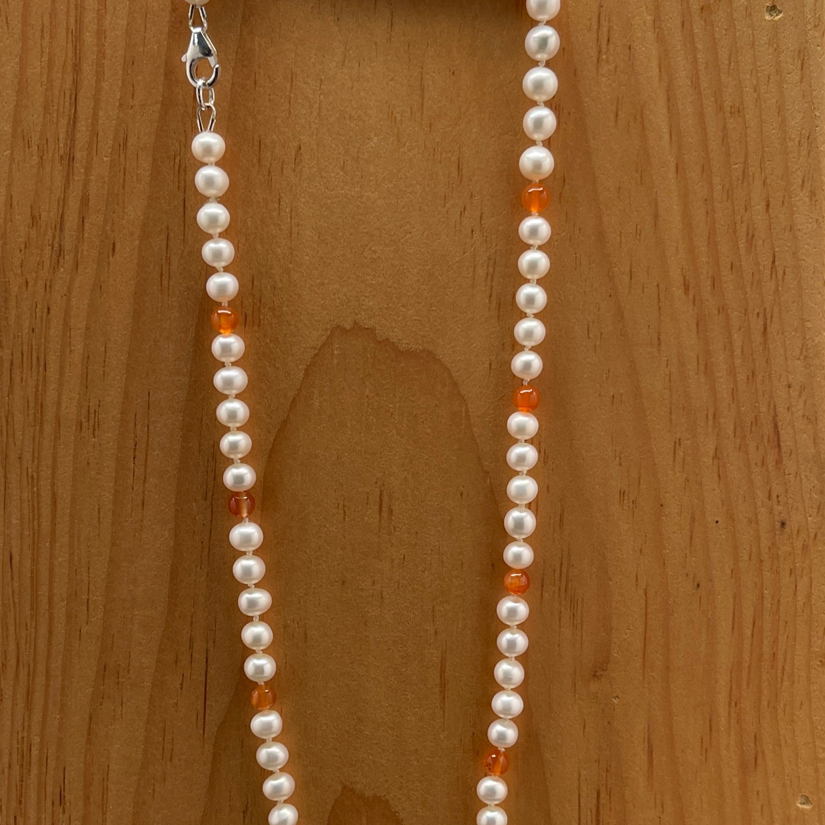 Pearl necklace with Carnelian beads on a wooden background