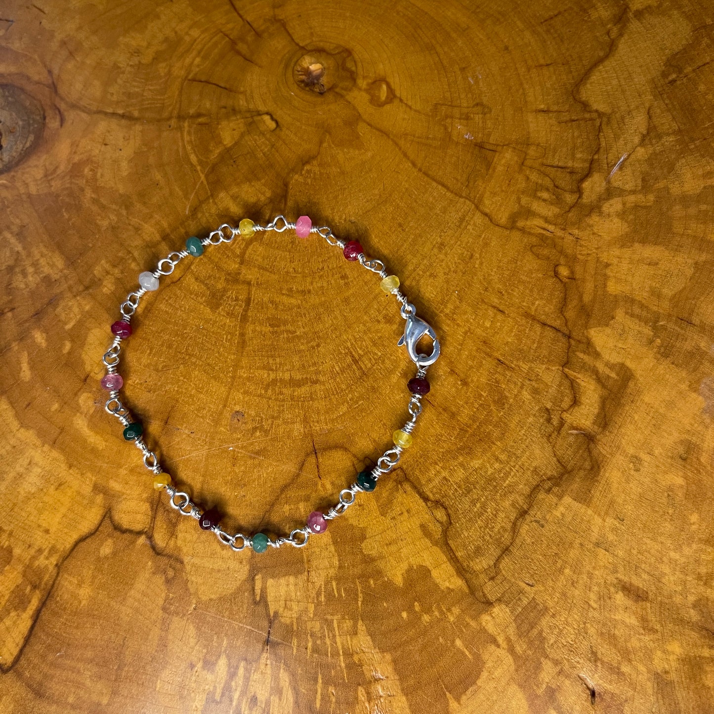 Multi Colored Jade on Sterling Silver wire with Sterling Silver Lobster clasp, 8" on wood