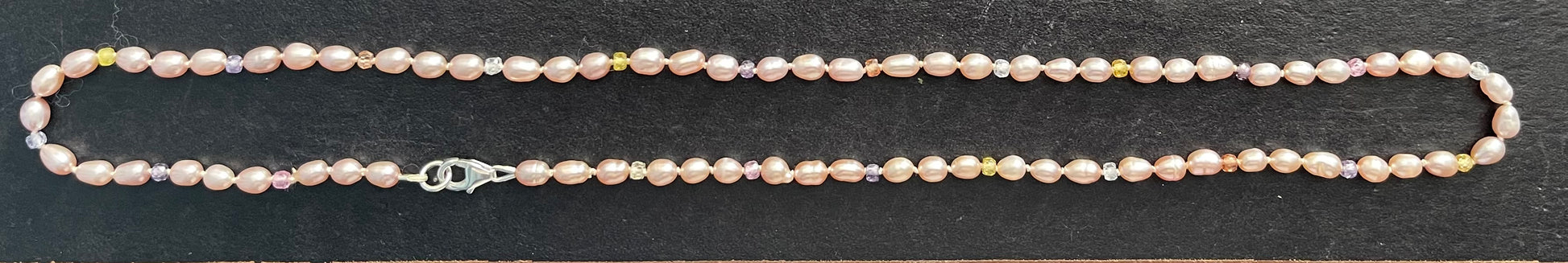 Pink Pearl  and multicolored cubic zirconia necklace on a dark surface