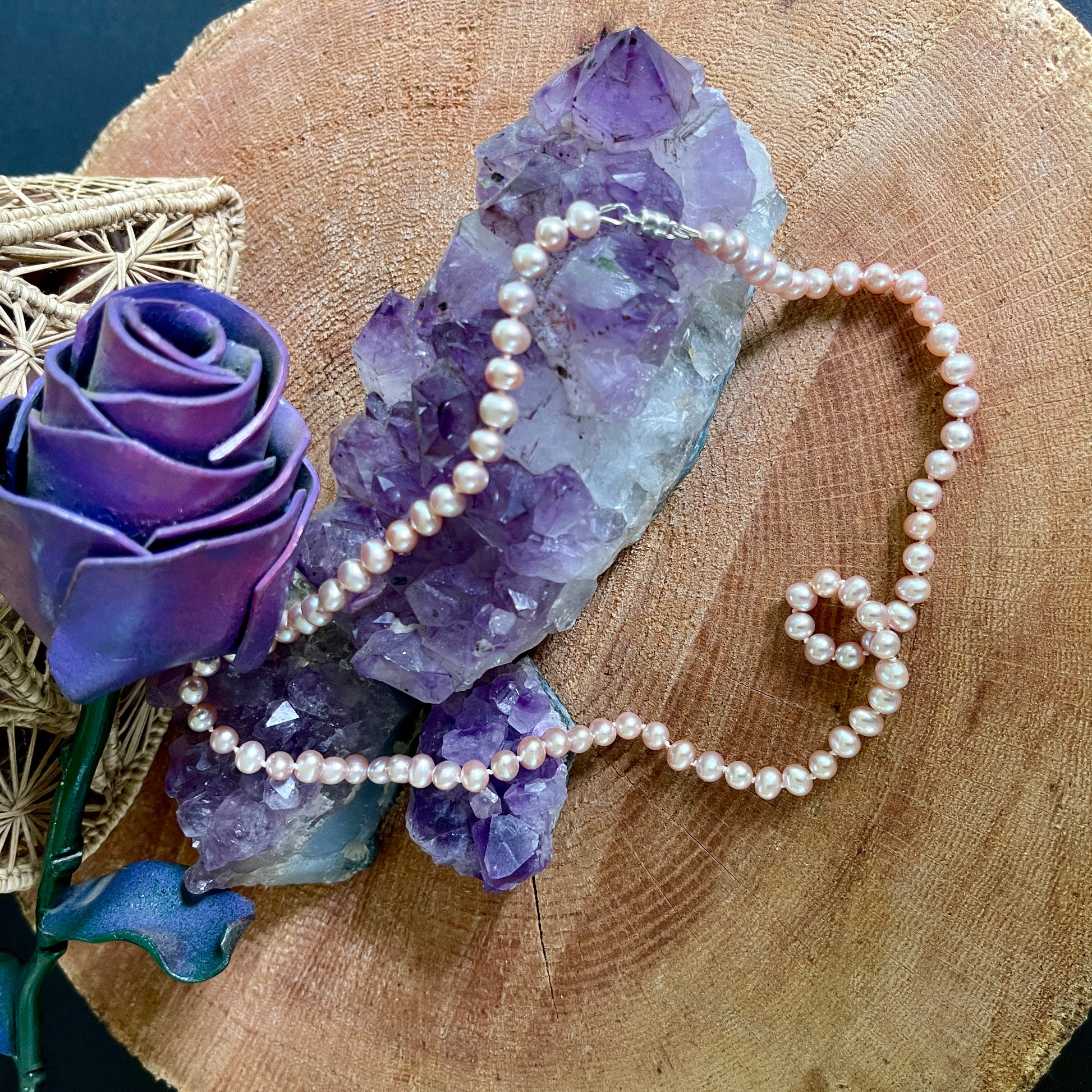 Pink Pearl necklace on a wooden surface with purple crystal and decorative rose
