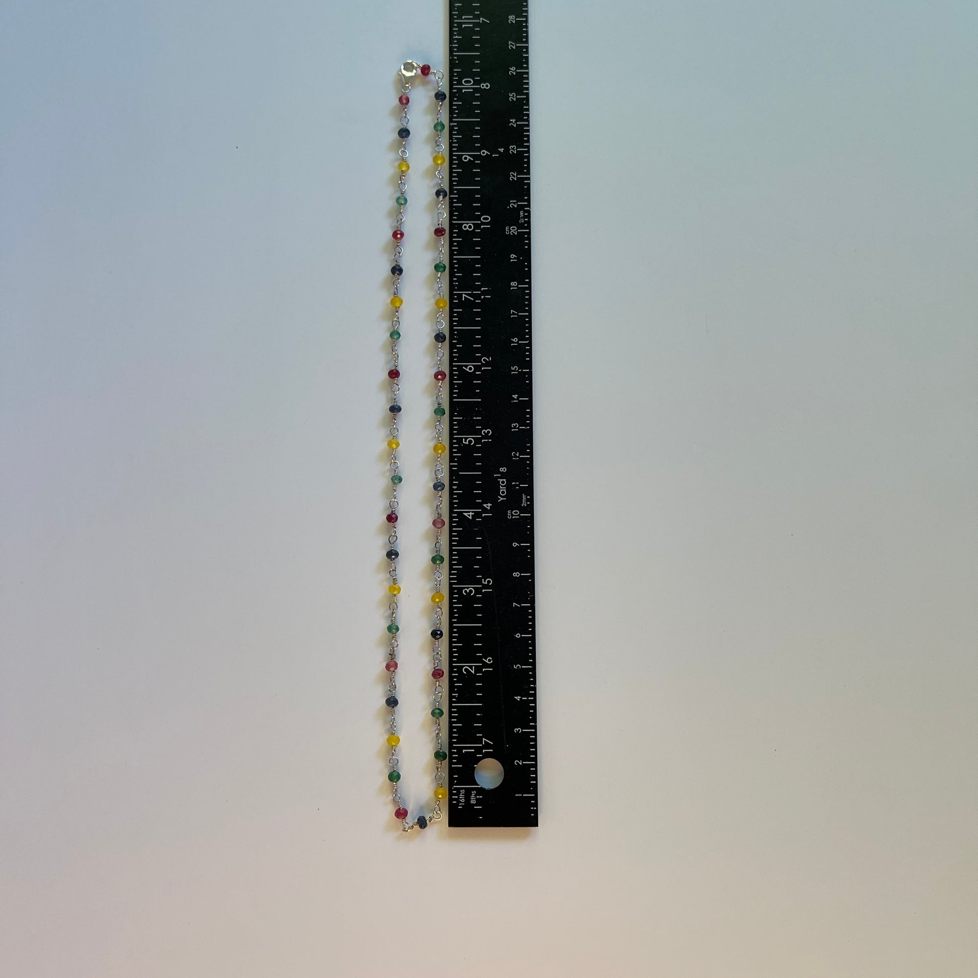 Necklace with multi colored Jade and White Pearl hand tooled on Sterling Silver wire on a white surface with ruler.