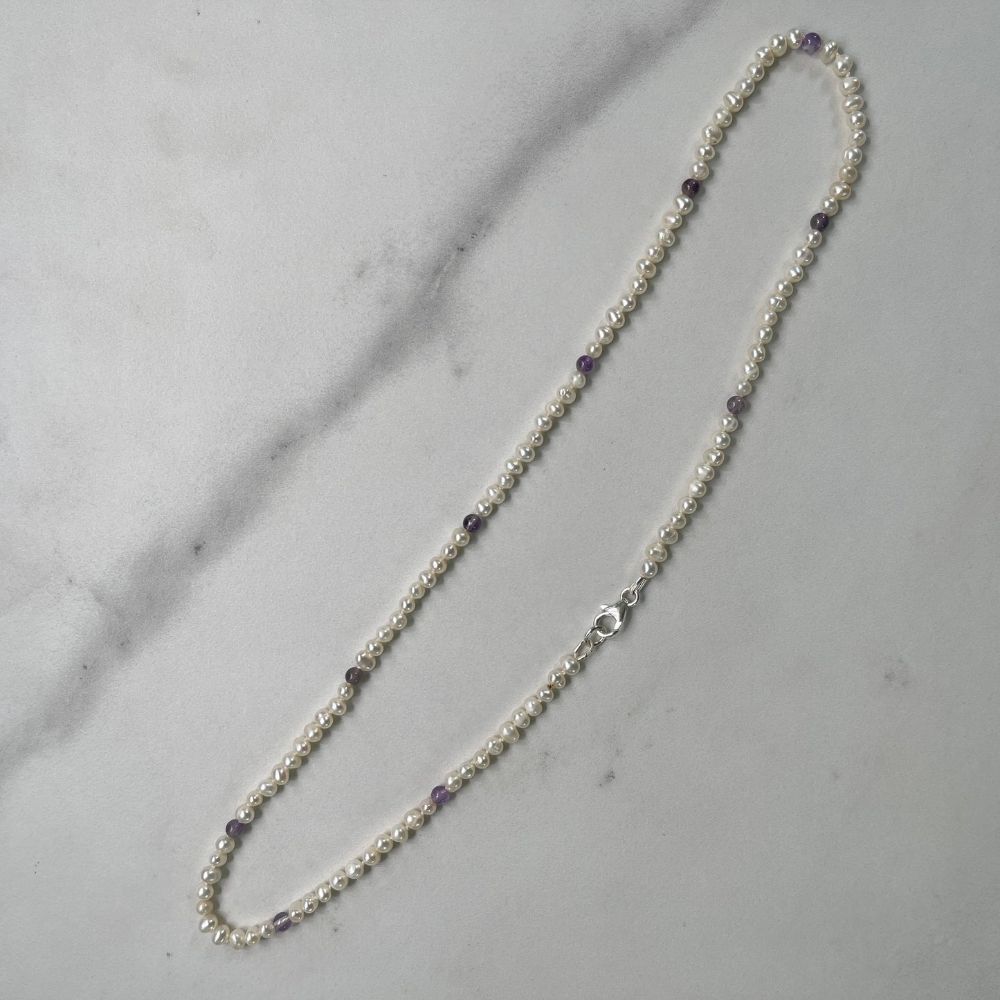 Pearl necklace with Amethyst beads on a marble surface