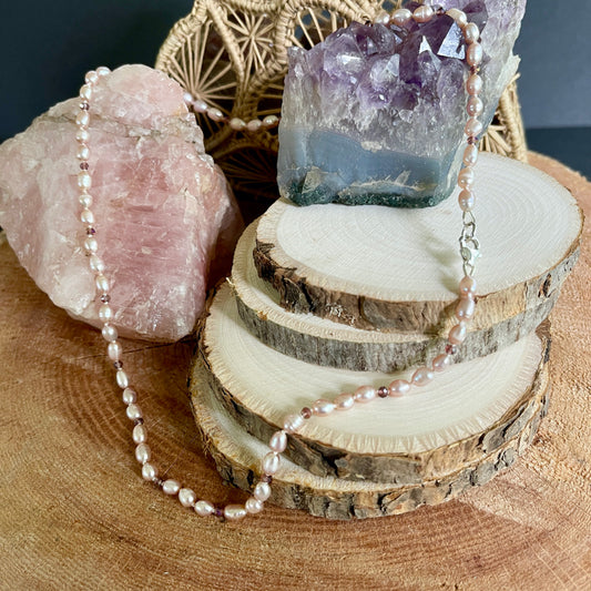 Pink Pearl and cubic zirconia necklace on a wooden surface with crystals and stones