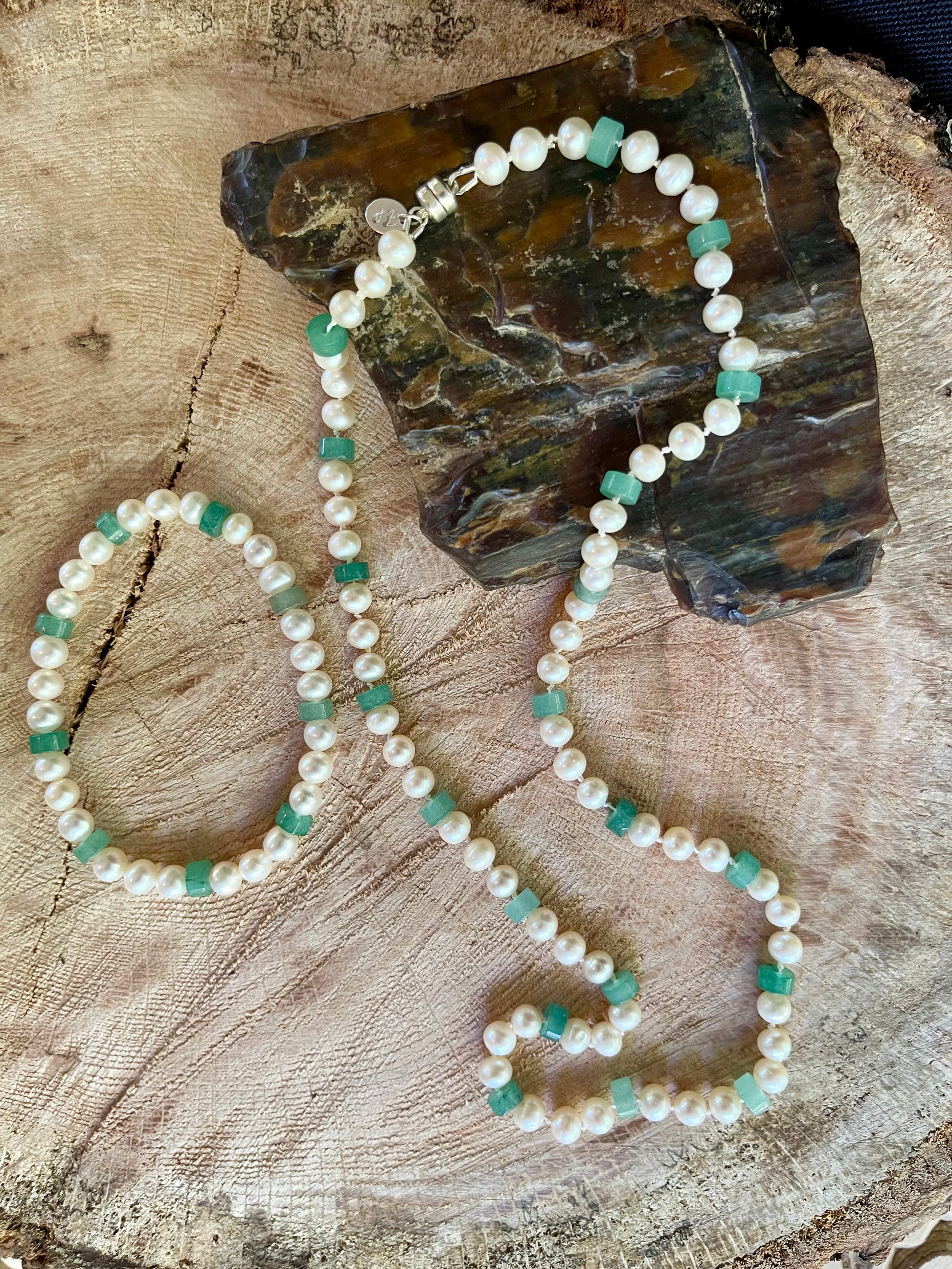 White round Pearls and Aventurine heishi discs beaded necklace and matching stretchy bracelet on a wooden surface with natural elements
