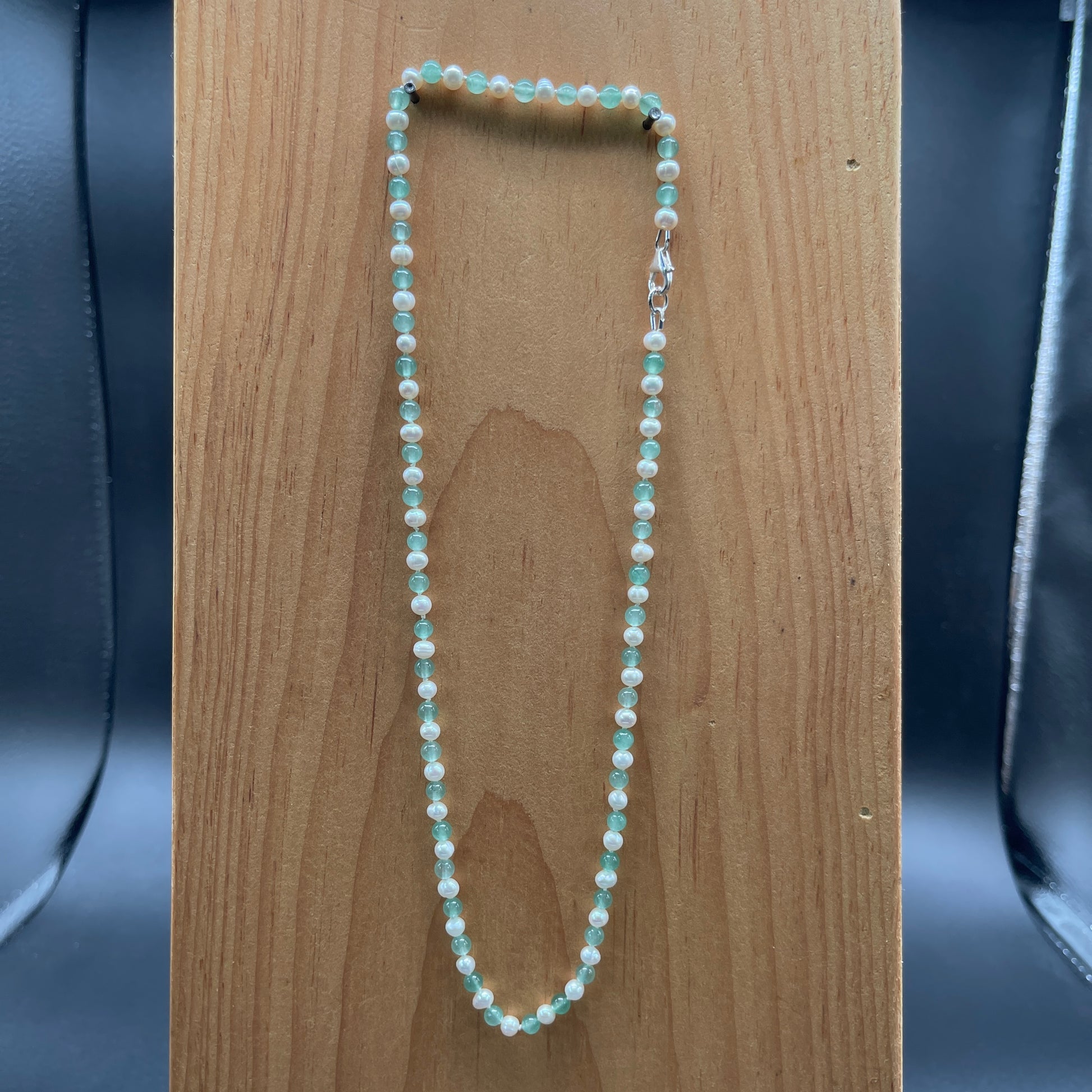 Necklace with green aventurine beads and white freshwater Pearls on a wooden surface 