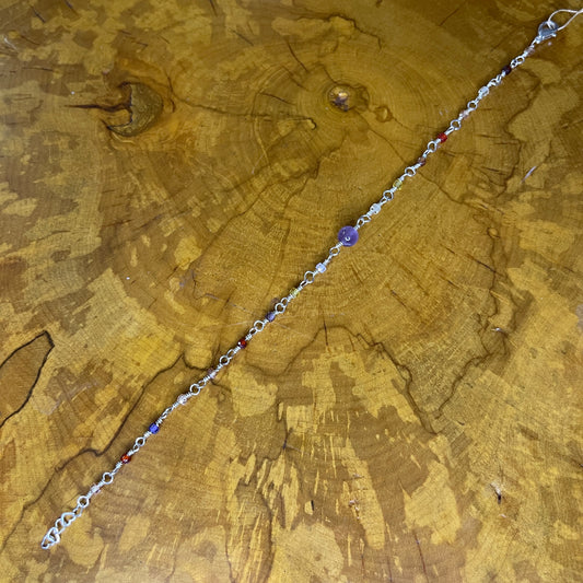 Multi colored Cubic Zirconia with Amethyst focus bead on Sterling Silver wire with Sterling Silver 1/2" heart chain  extender, 9" on wooden slab