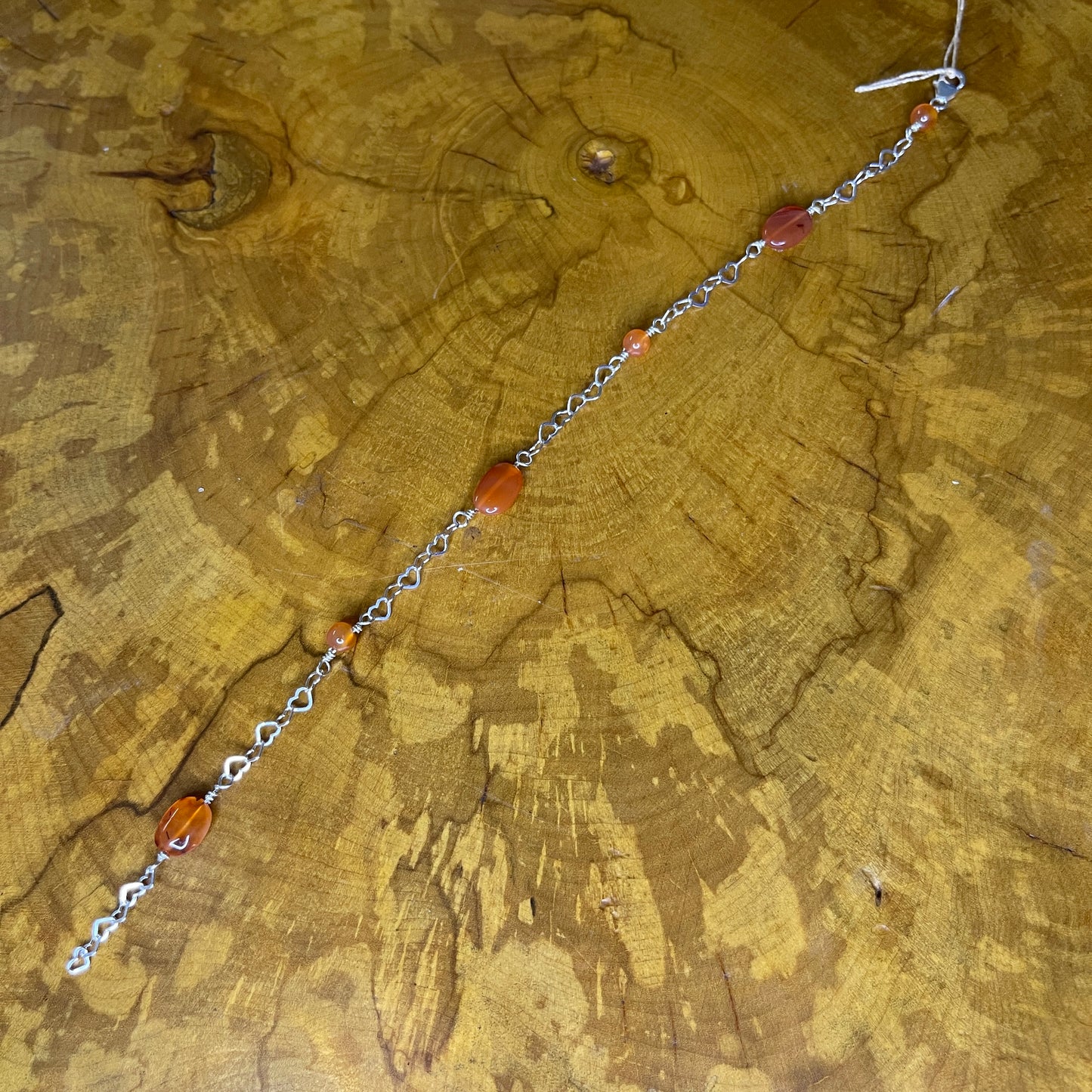 Carnelian Oval and Rounds on Sterling Silver Heart Chain, 8 inches with 1/2 inch extender, Sterling Silver lobster clasp on wooden surface