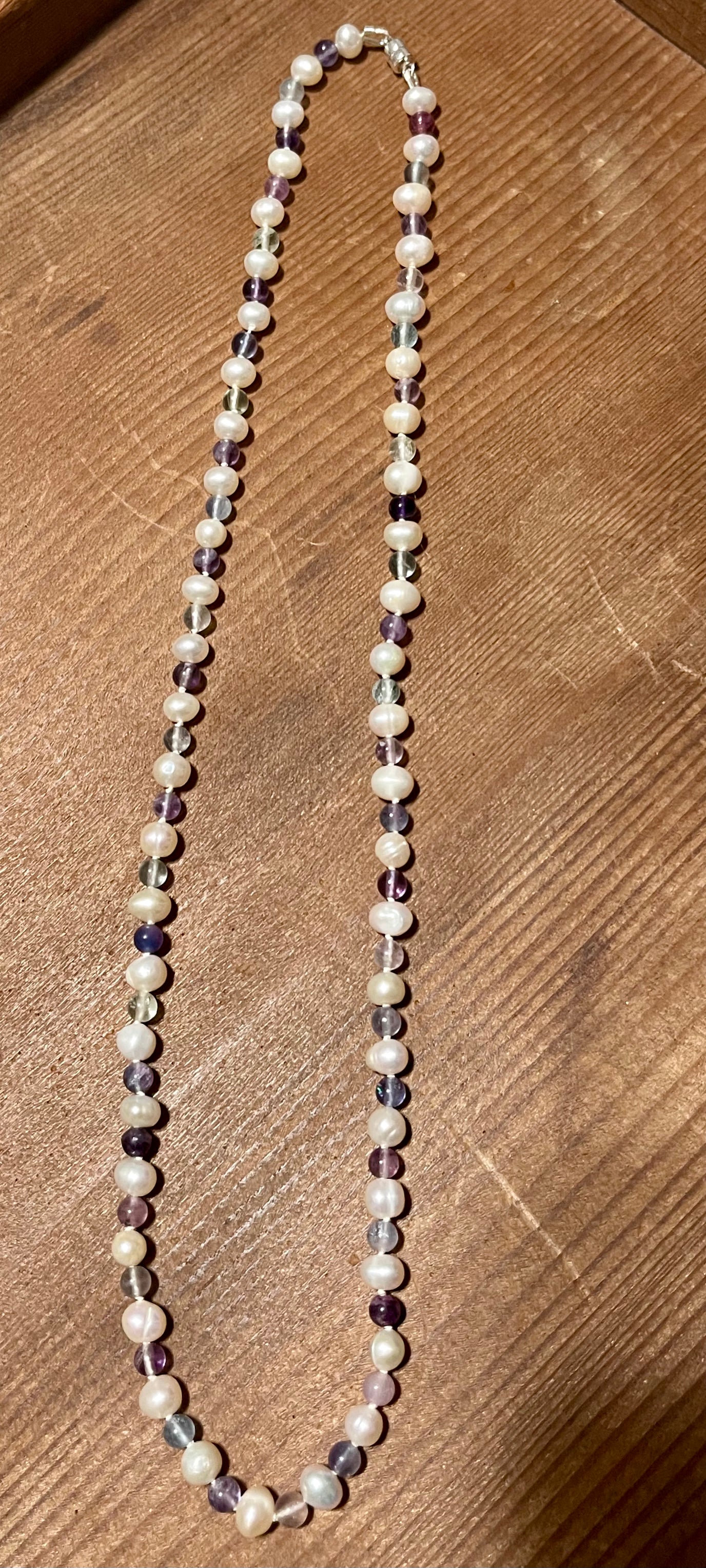 Necklace with alternating white Pearls and Fluorite beads on a wooden surface