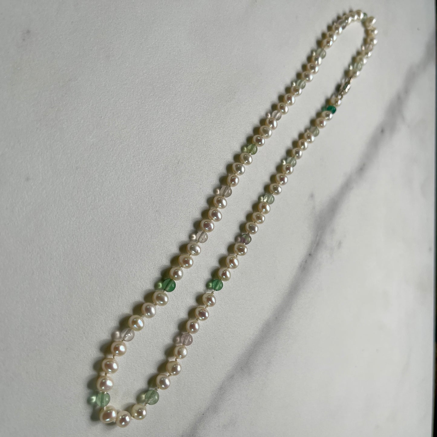 Pearl necklace with fluorite accents on a light gray background