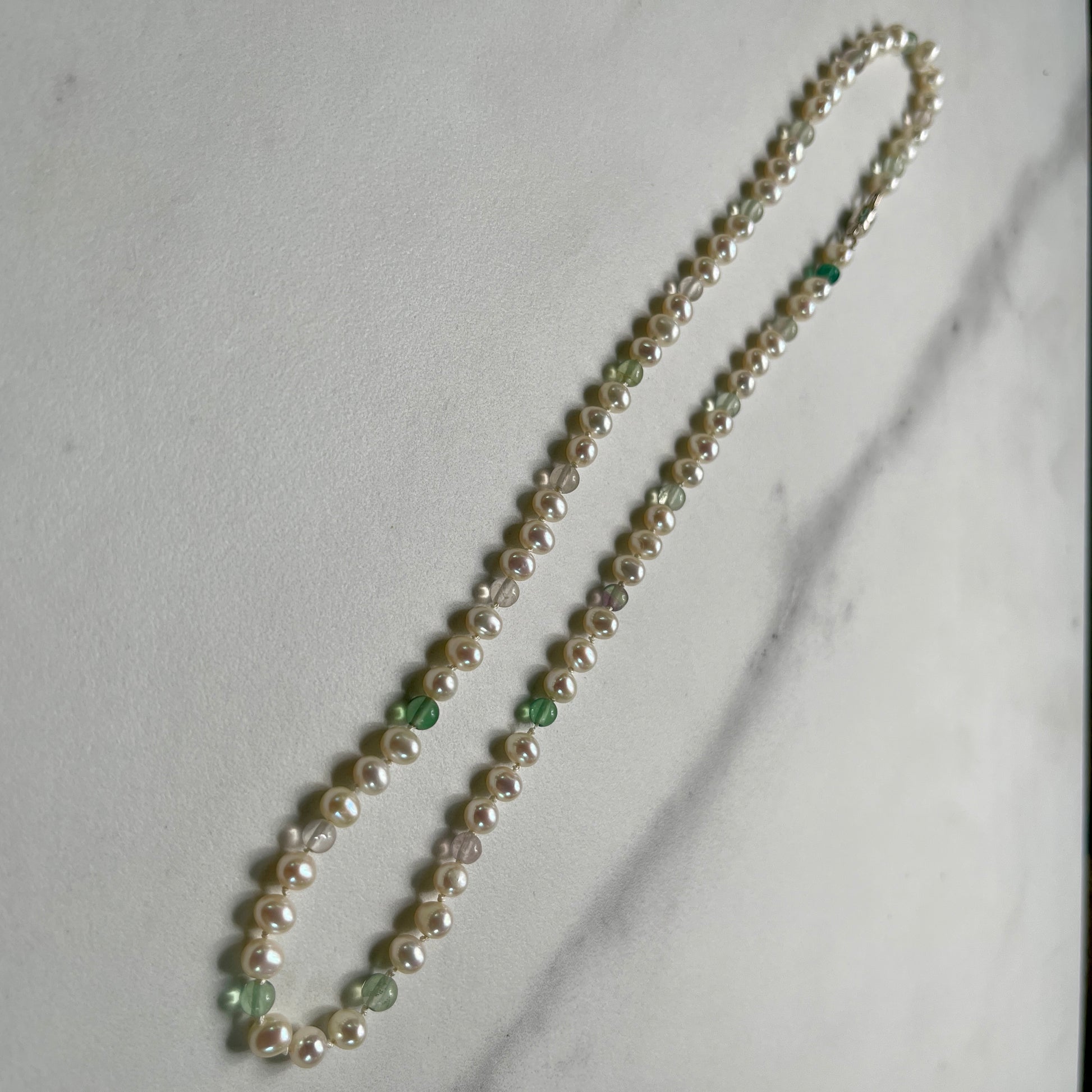 Pearl necklace with fluorite accents on a light gray background