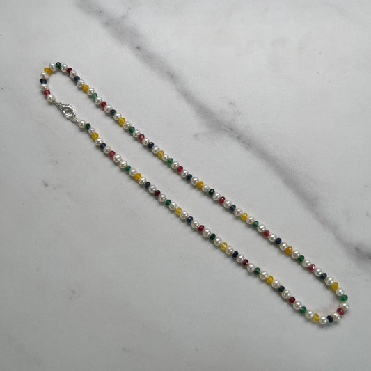 Multicolored  Jade and white Pearl beaded necklace on a light gray surface