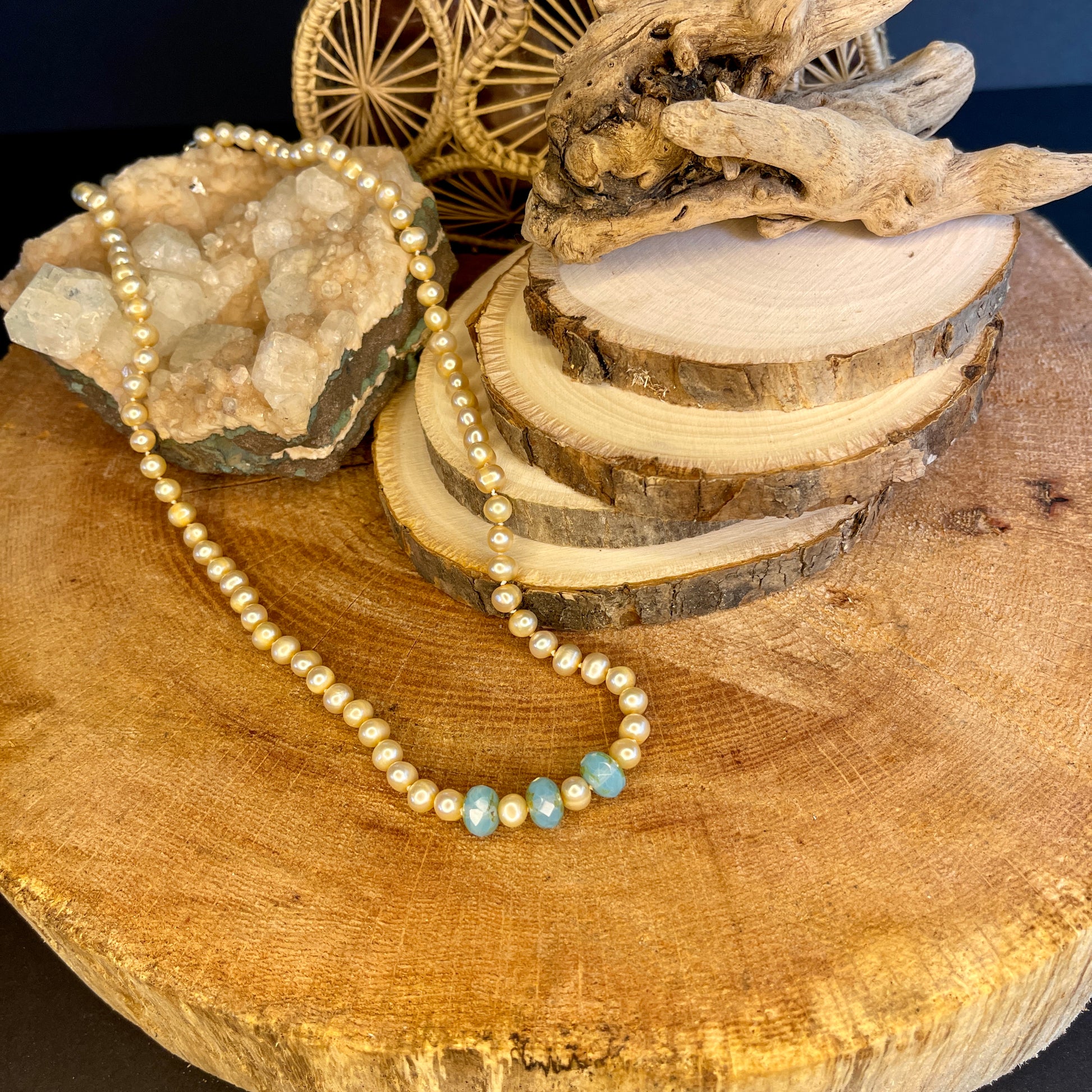 Pink pearl and Blue Chalcedony accented necklace on wood with crystal
