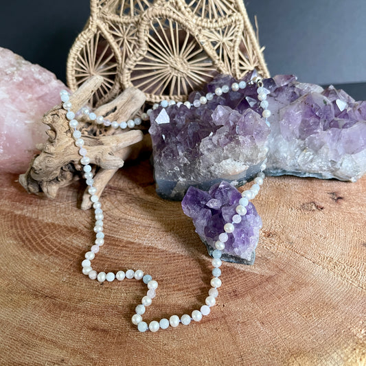 Pearl  and Morganite necklace on a wooden surface with amethyst crystals