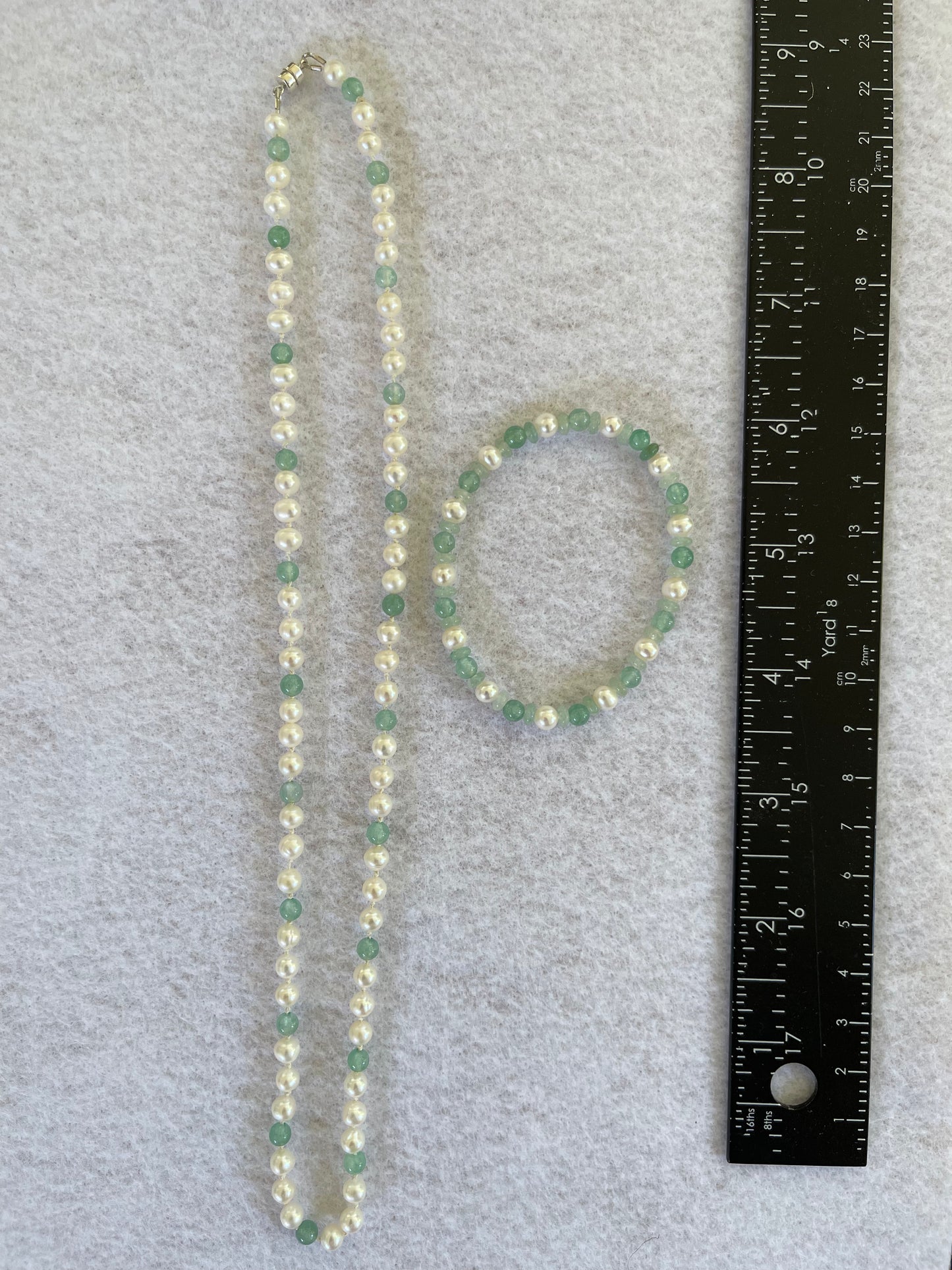 White Pearl and green aventurine beaded necklace and bracelet set on white background with ruler