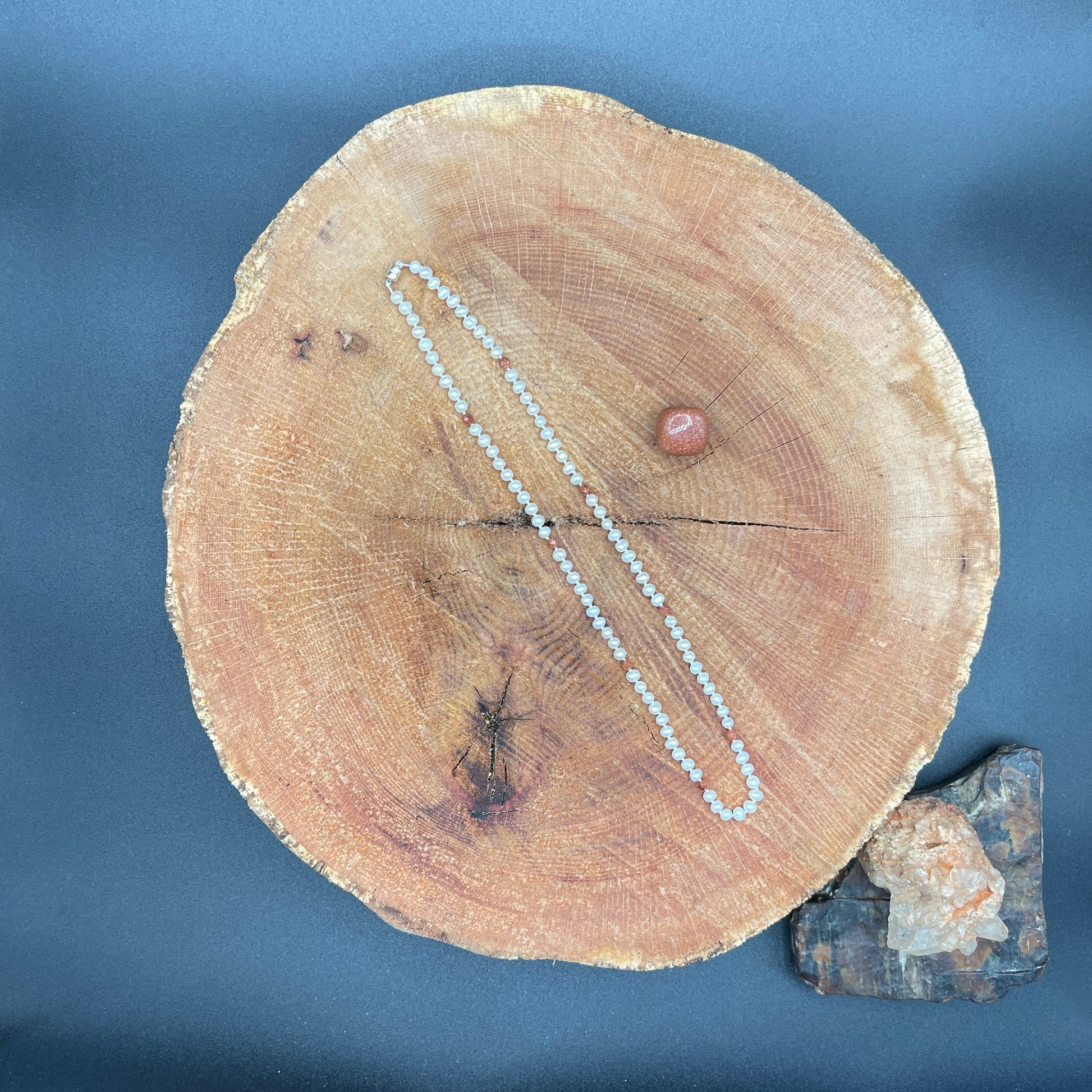 Wooden log with a necklace draped over it on a blue background