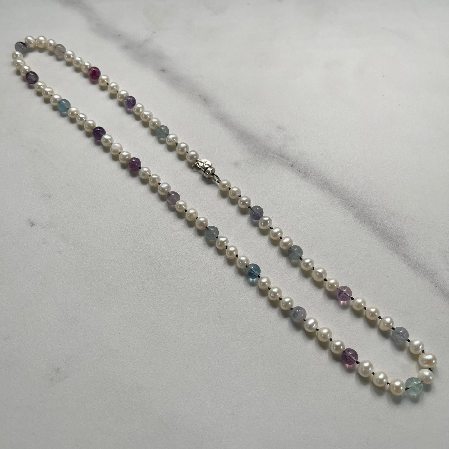 Pearl necklace with Fluorite beads on a light gray surface