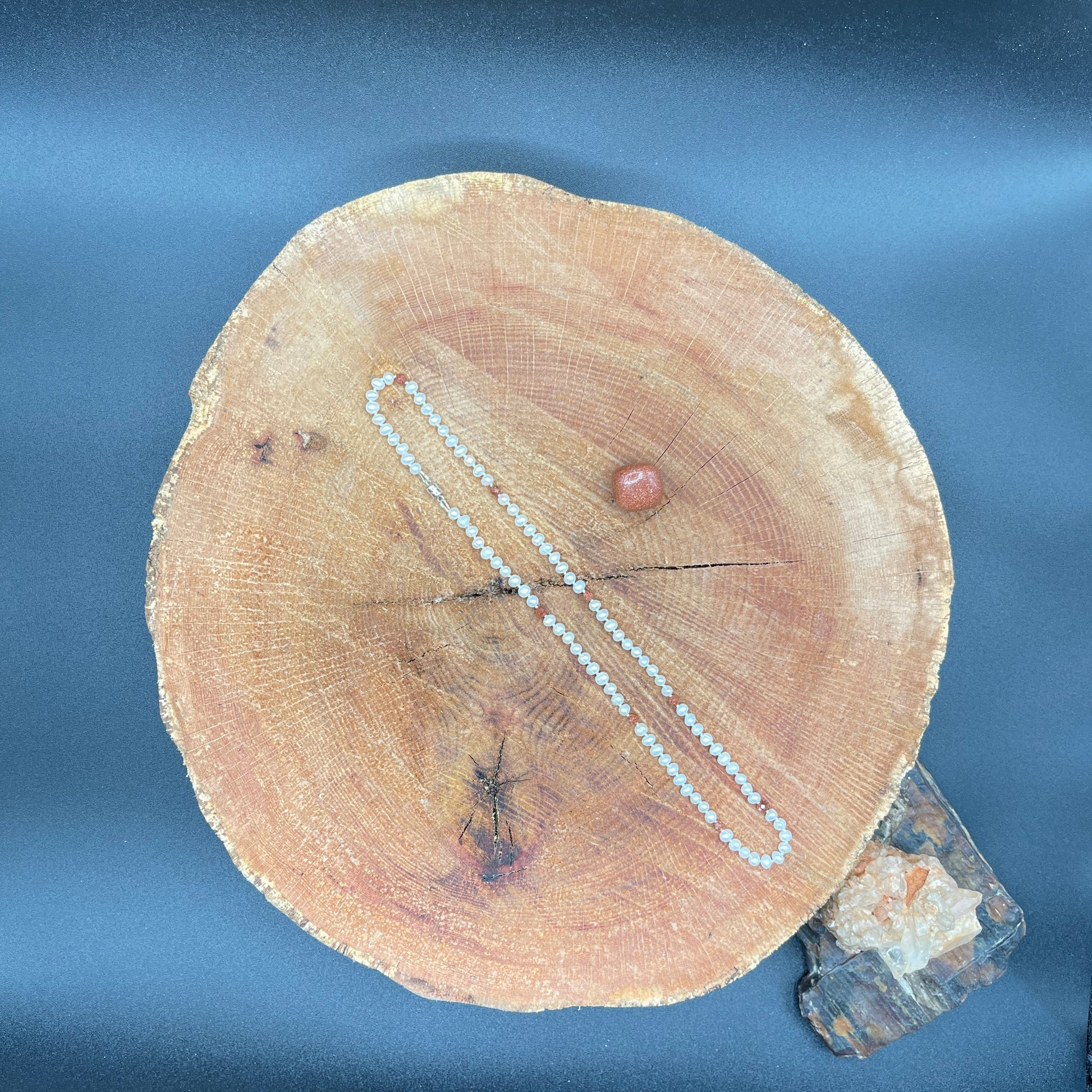 Pearl  and goldstone necklace on a wooden surface with a stone
