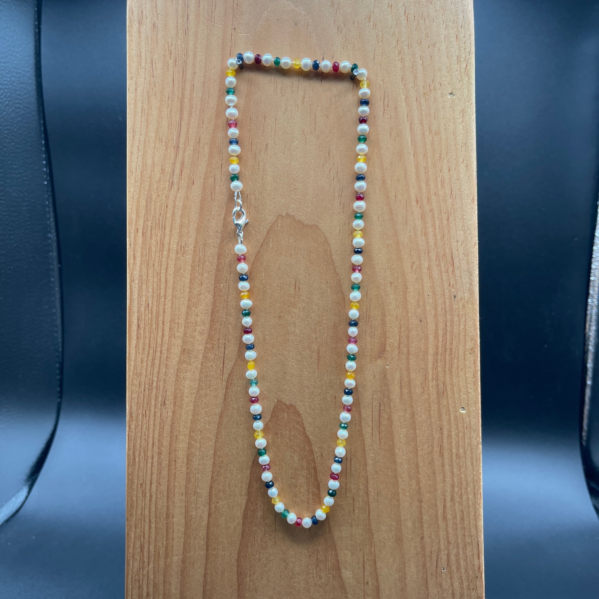 Multicolored  Jade and white Pearl beaded necklace on wood