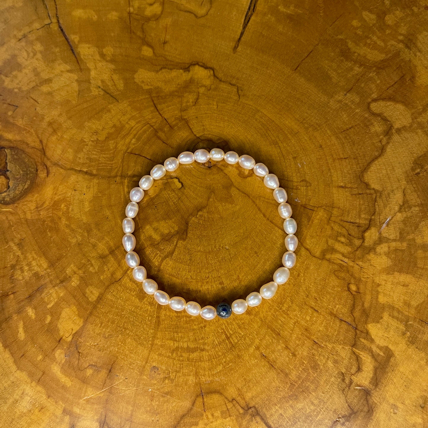 Mauve freshwater Pearls with Blue kyanite focus bead on elastic, 7 1/2" on elastic, 7 1/2" on wooden surface