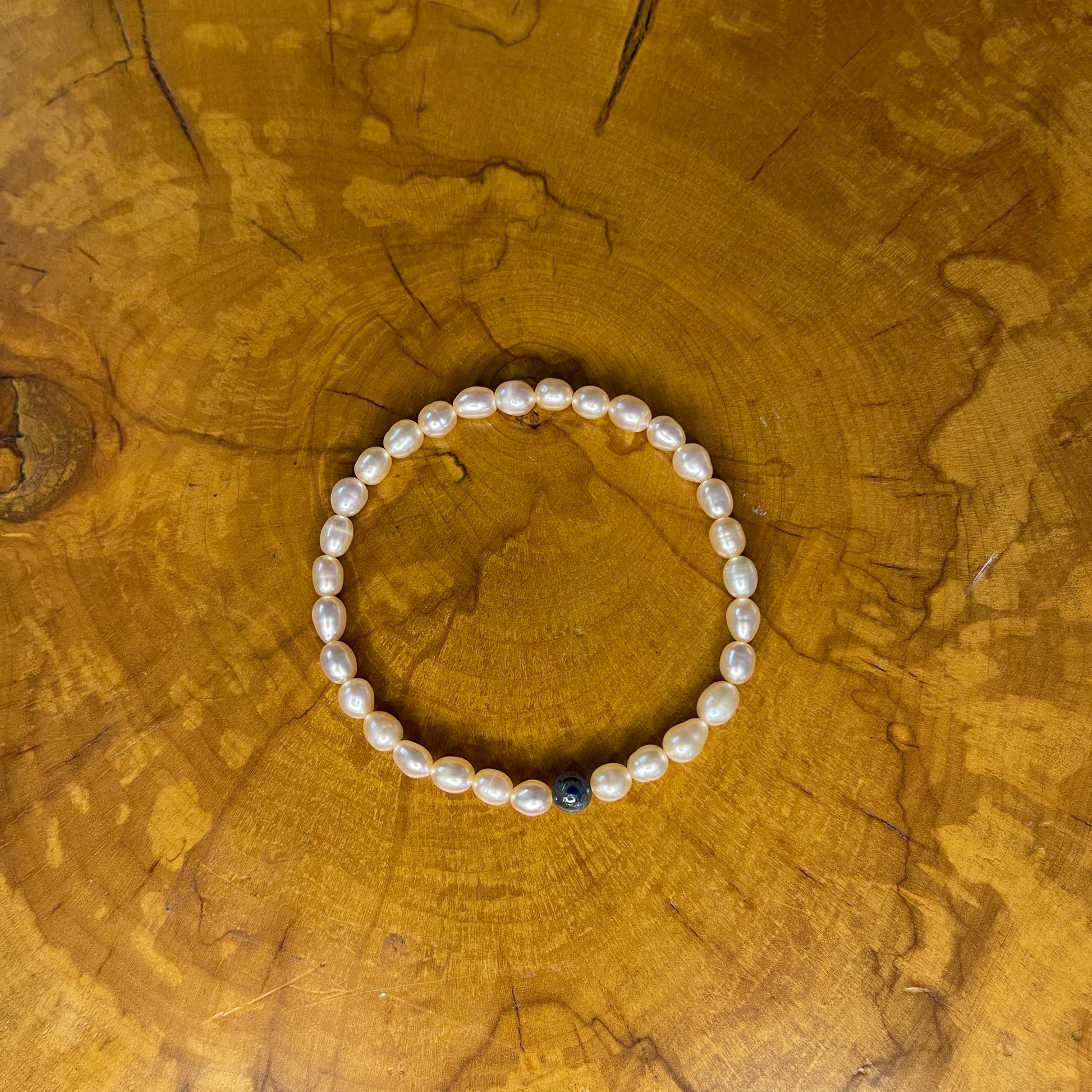 Mauve freshwater Pearls with Blue kyanite focus bead on elastic, 7 1/2" on elastic, 7 1/2" on wooden surface
