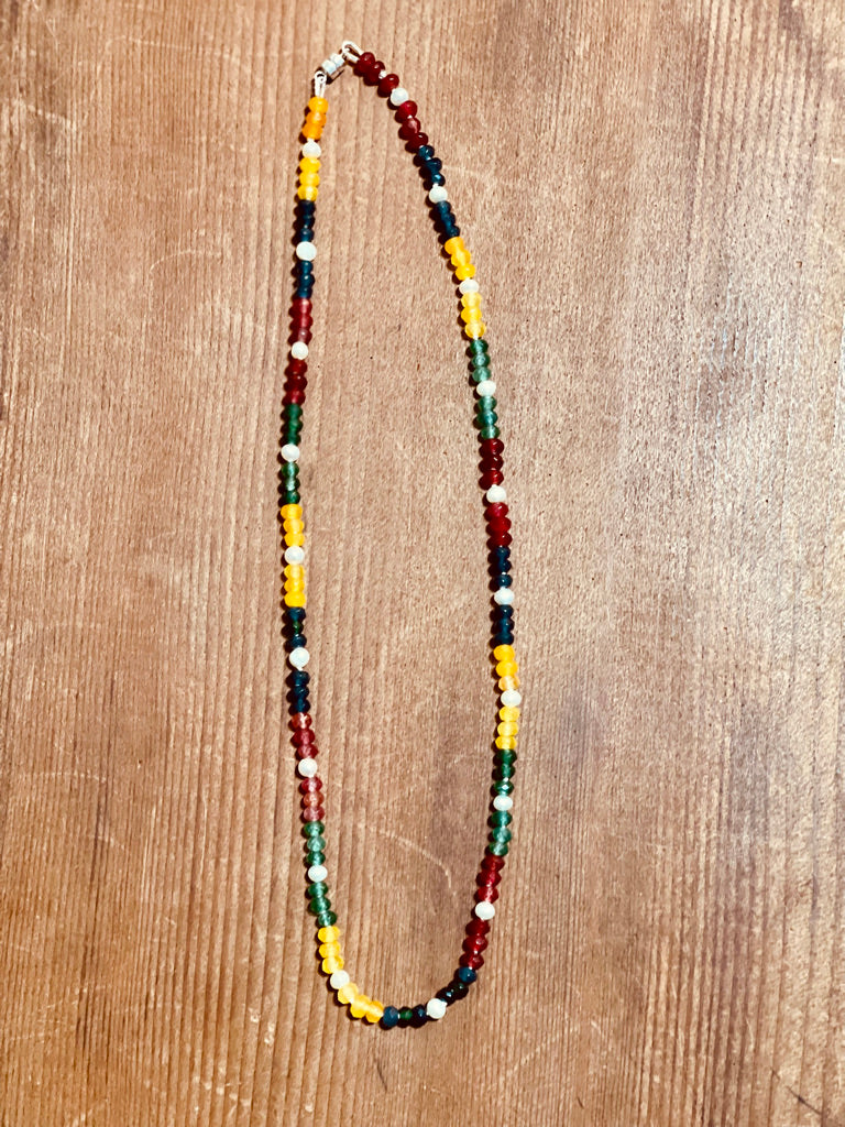 Multi colored Jade and white Pearl Beaded necklace on a wooden surface