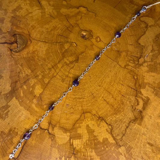 Faceted Amethyst and rounds on Sterling Silver Heart Chain with Sterling Silver lobster clasp on a wooden surface