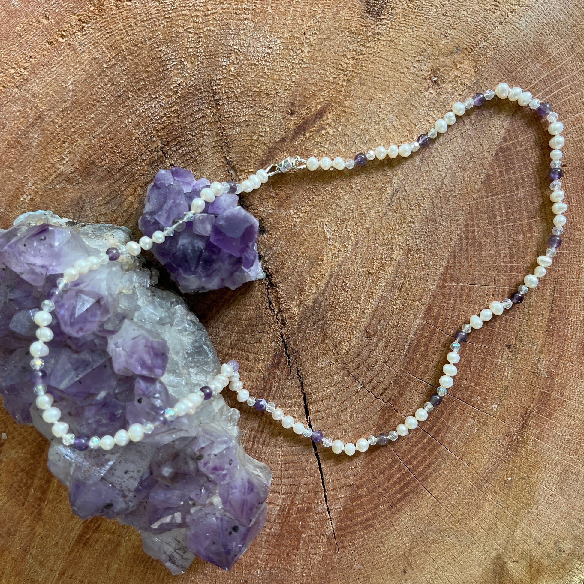 Necklace with white Pearls, Amethyst and crystals on a wooden surface