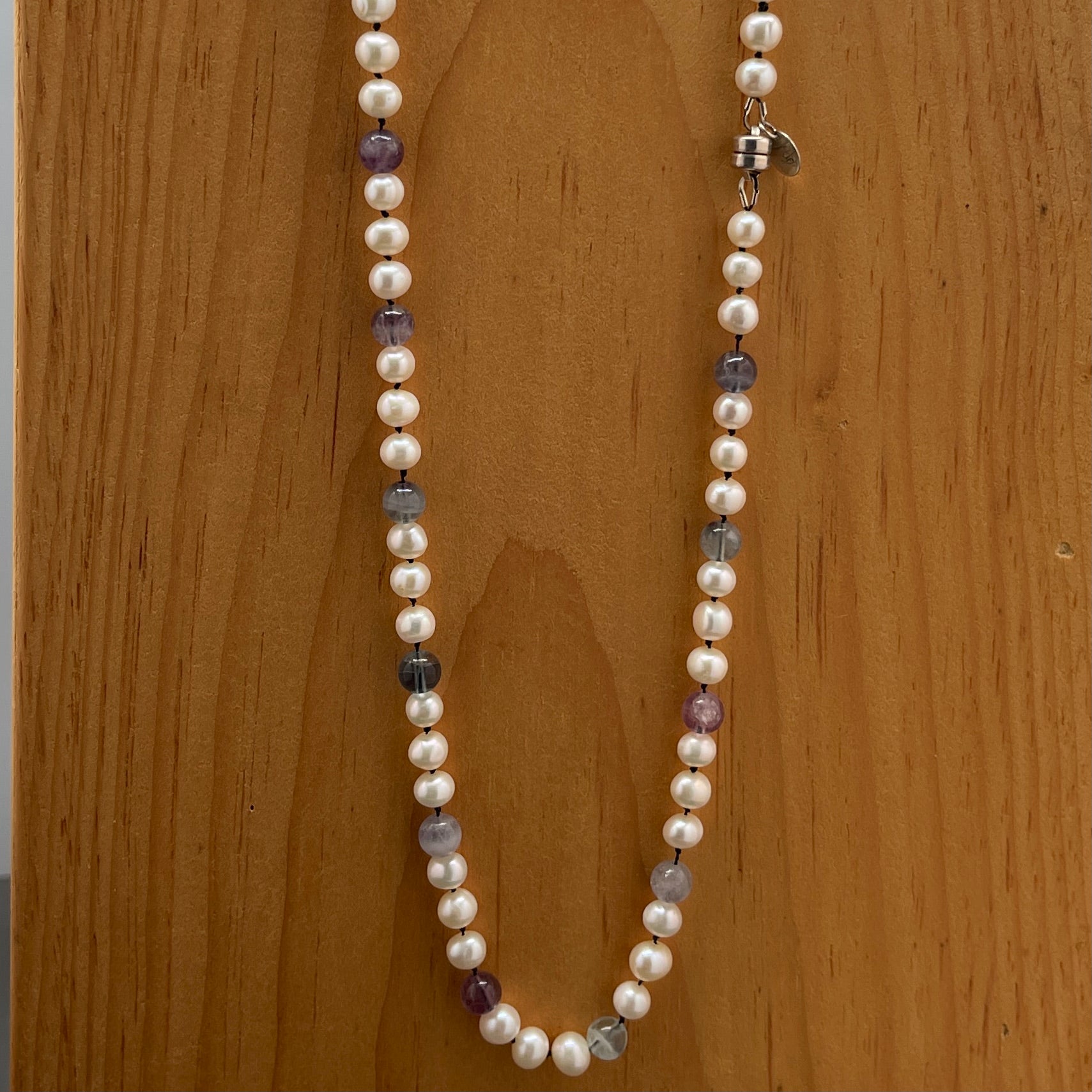 Pearl necklace with Fluorite on black Silk on a wooden surface