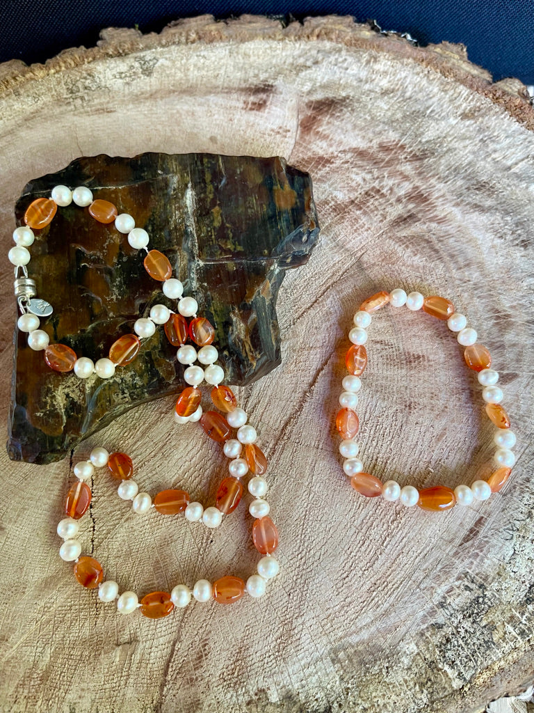 Necklace with White Pearls and oval Carnelian beads  with matching stretchy bracelet on a wooden surface with petrified wood