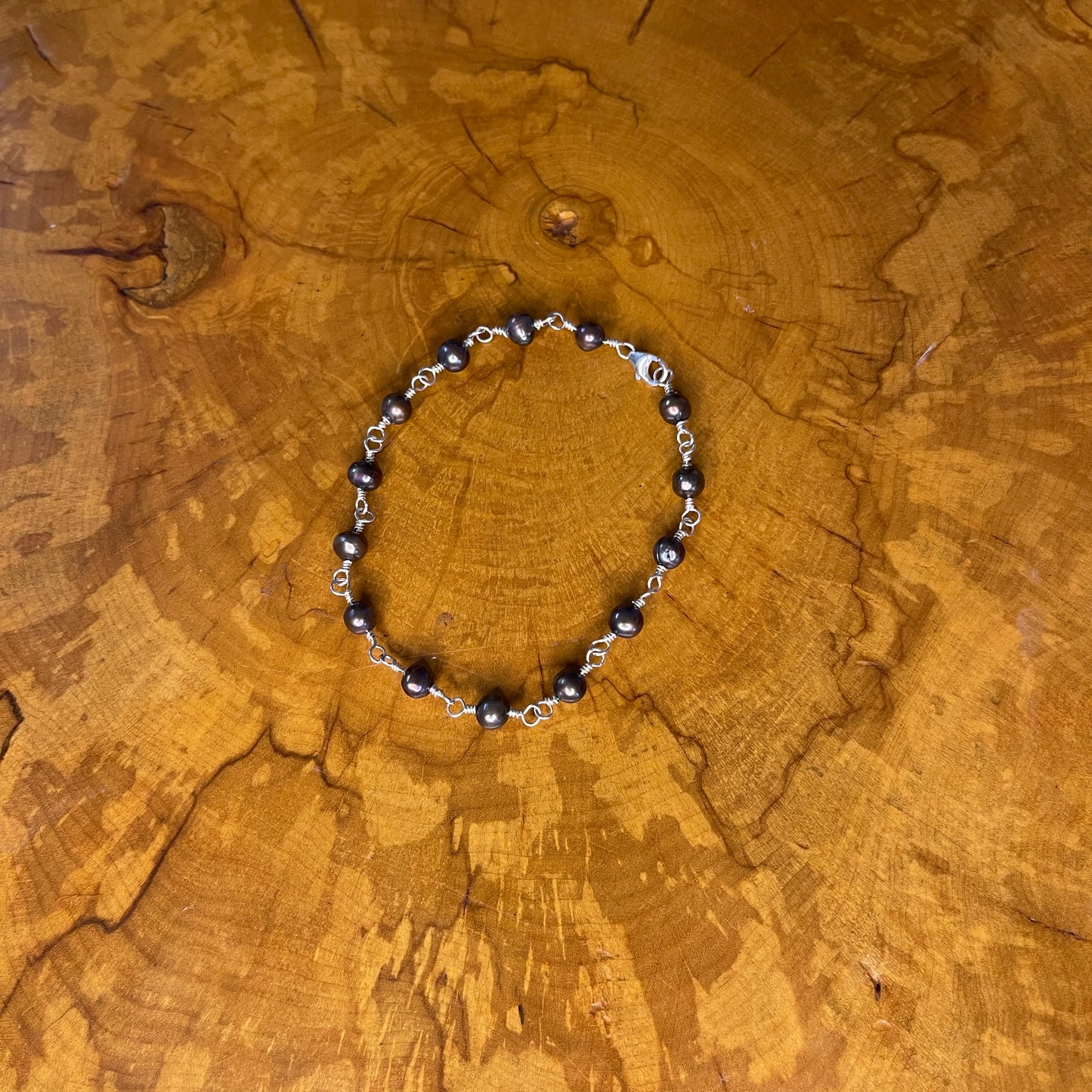 Dark Peacock freshwater Pearls on Sterling Silver wire with Sterling silver lobster clasp, 8" on wood