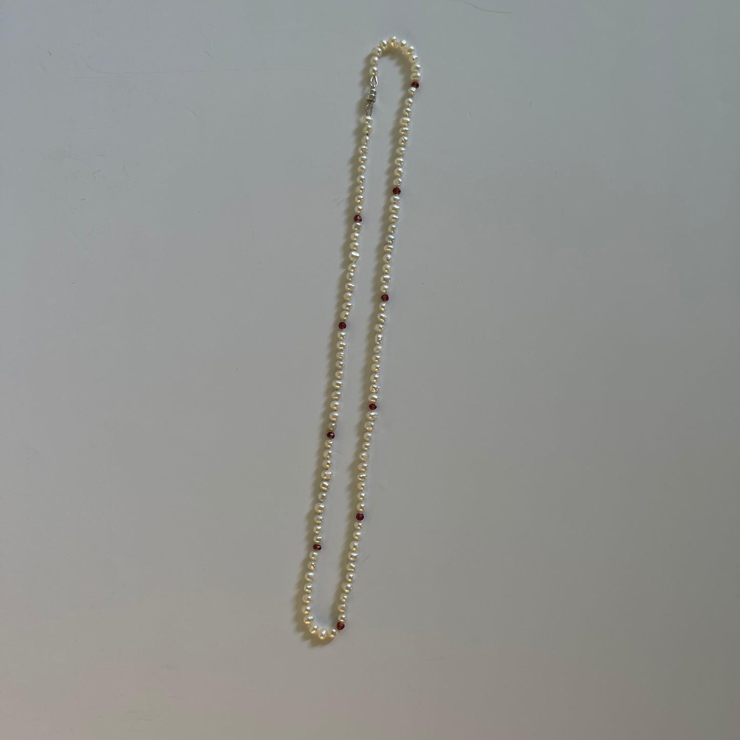 Pearl  and red cubic zirconia necklace with a white background